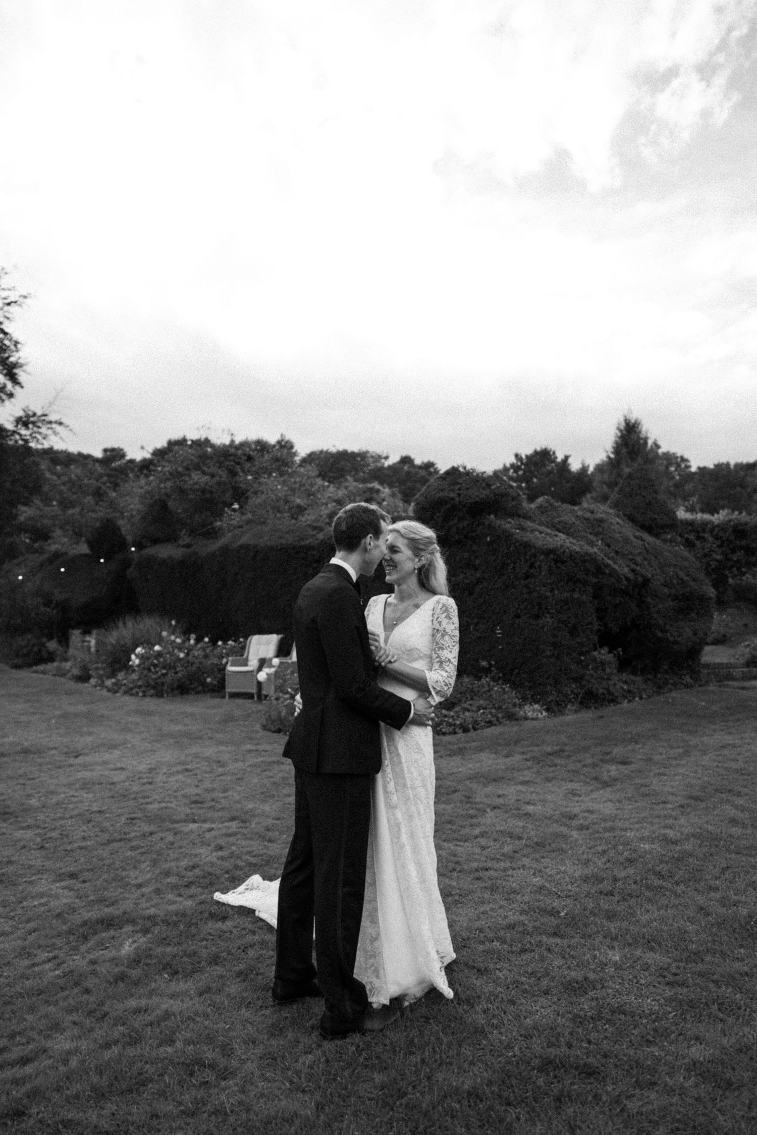 B&W photo of bride & groom heads together on a field