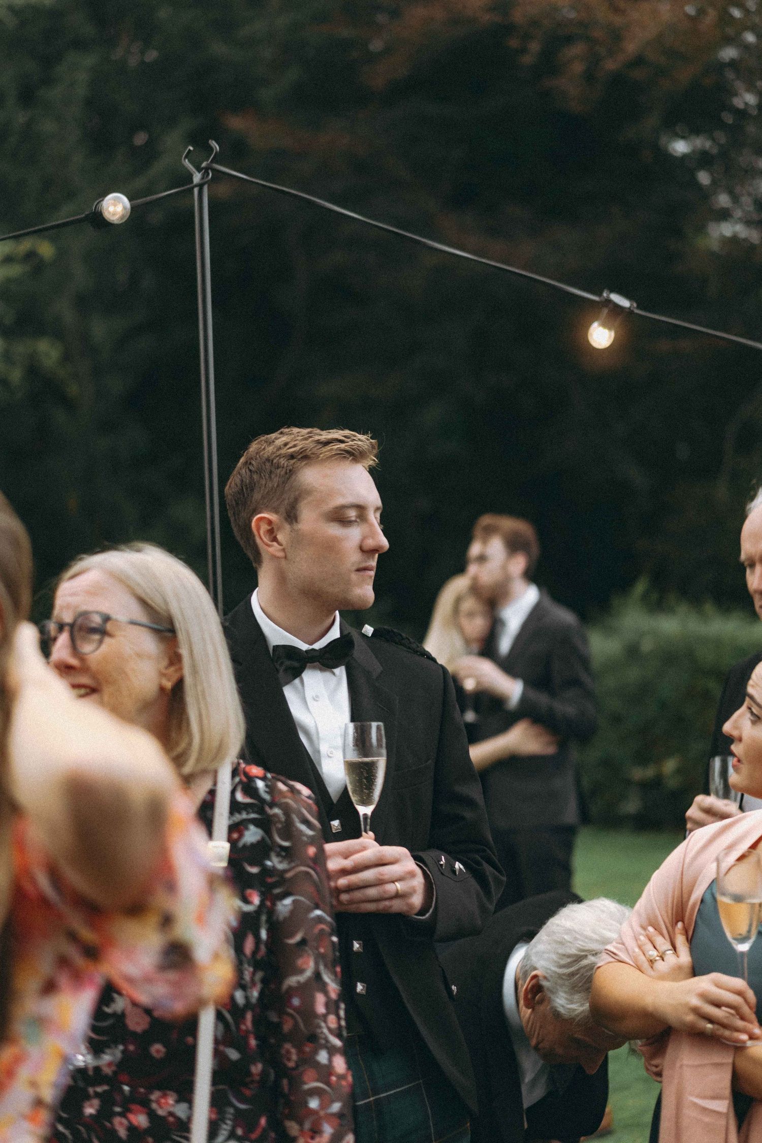 Candid photo of guest interacting and a couple in an embrace in the background