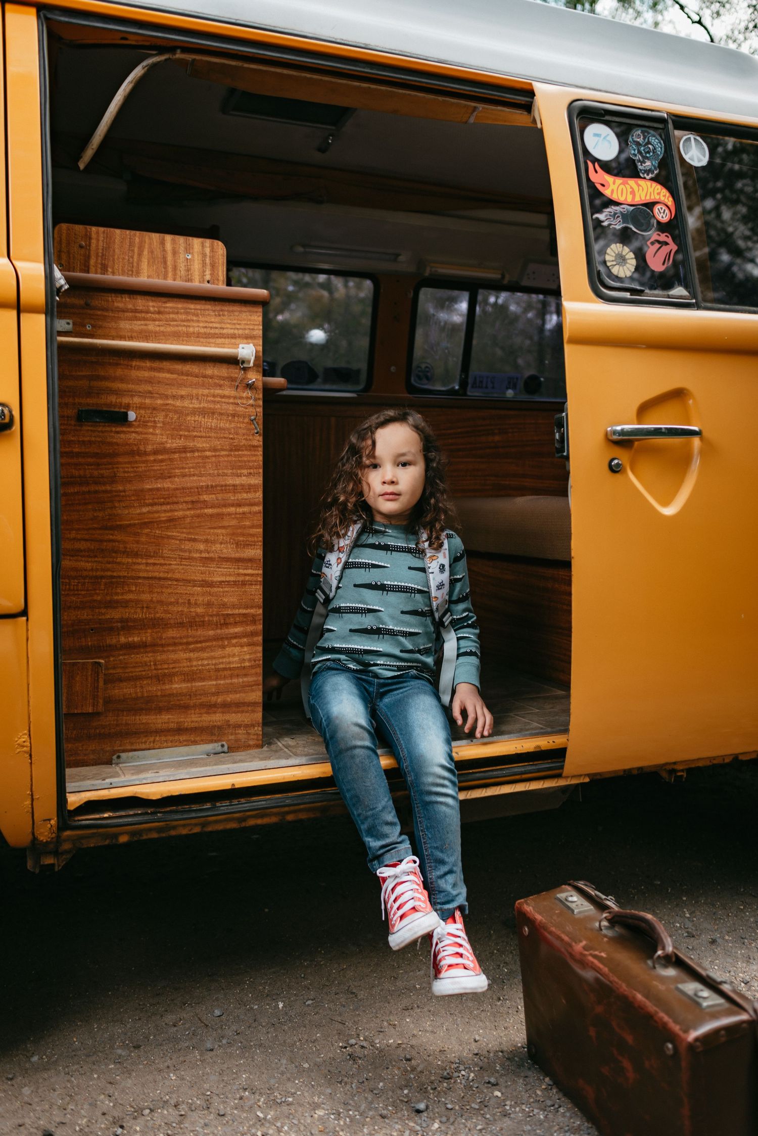 Child model sitting on floor of a yellow camper van. Product photography