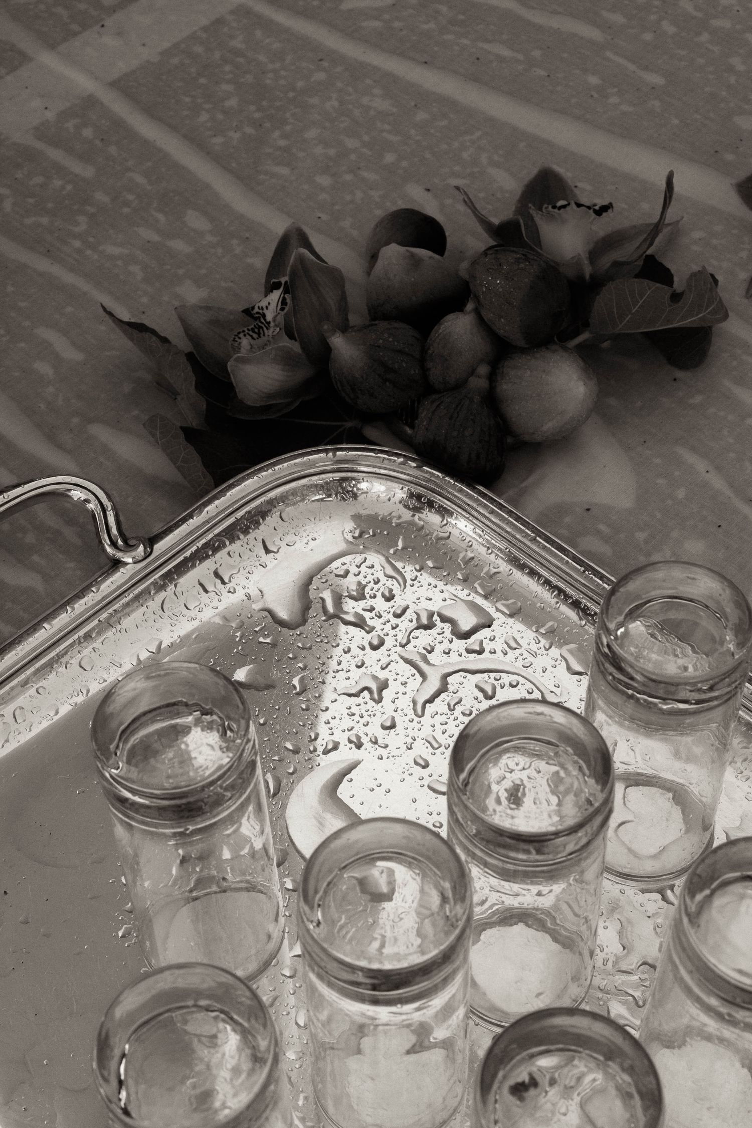 Multiple glass mason jars sit in a sink filled with water and soap suds during a washing process.