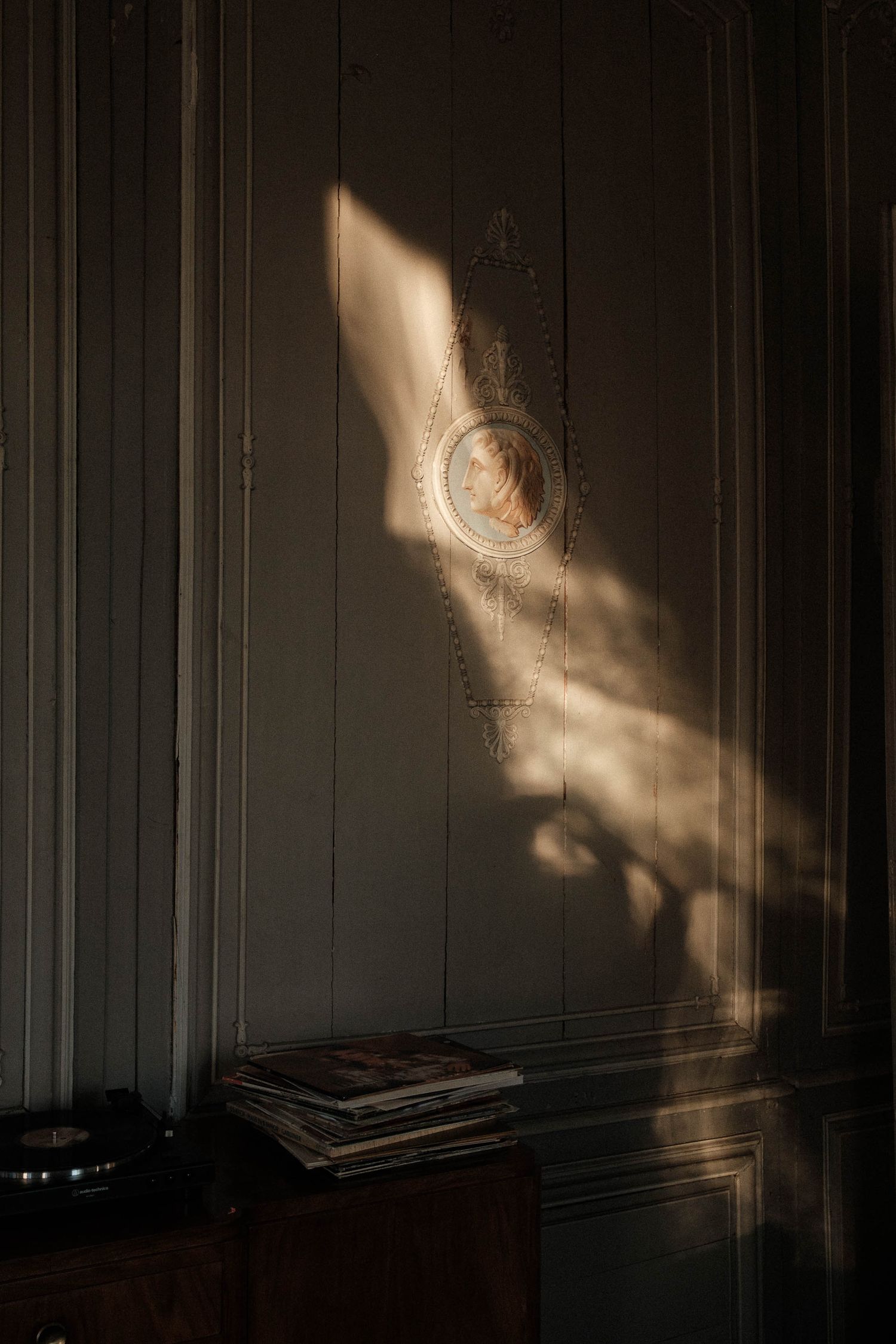 A series of abstract light reflections cast dramatic shadows on a dark wall creating an ethereal atmospheric effect.