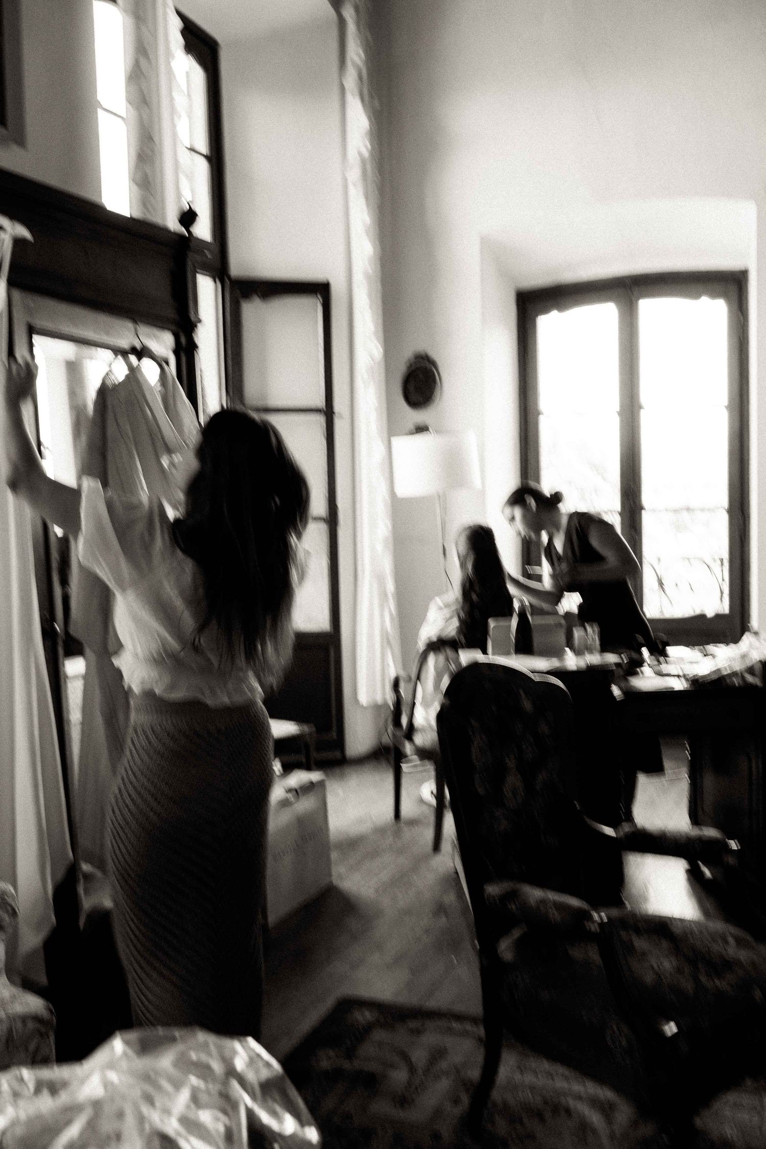 A series of black and white photos showing someone adjusting curtains near a window in an interior room.