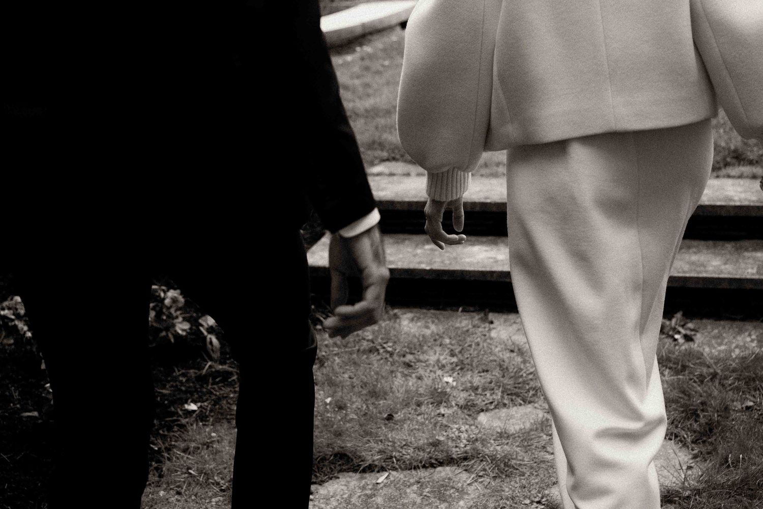 A black and white photo showing contrasting dark and light formal attire legs standing on grass.