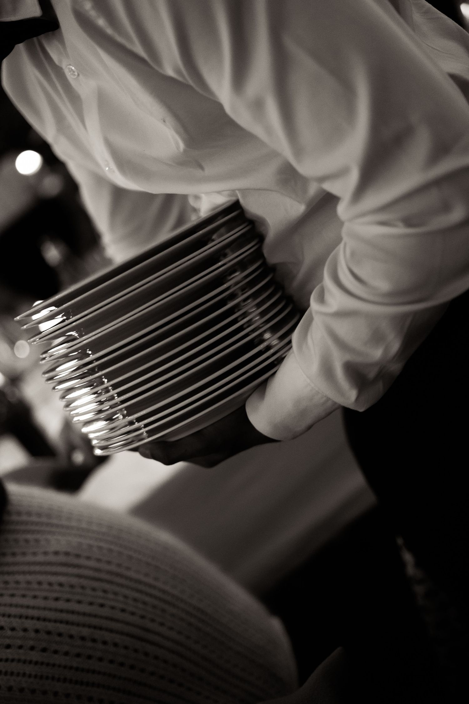 A gloved hand carefully arranges metal surgical pins in a black and white medical photograph.
