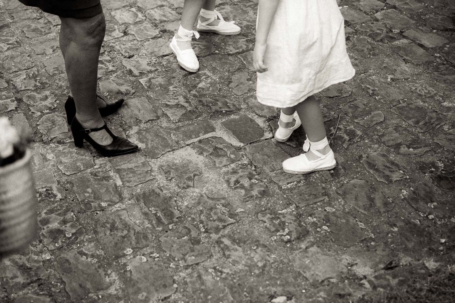 A series of black and white photos showing feet and legs of people walking on a cobblestone street.