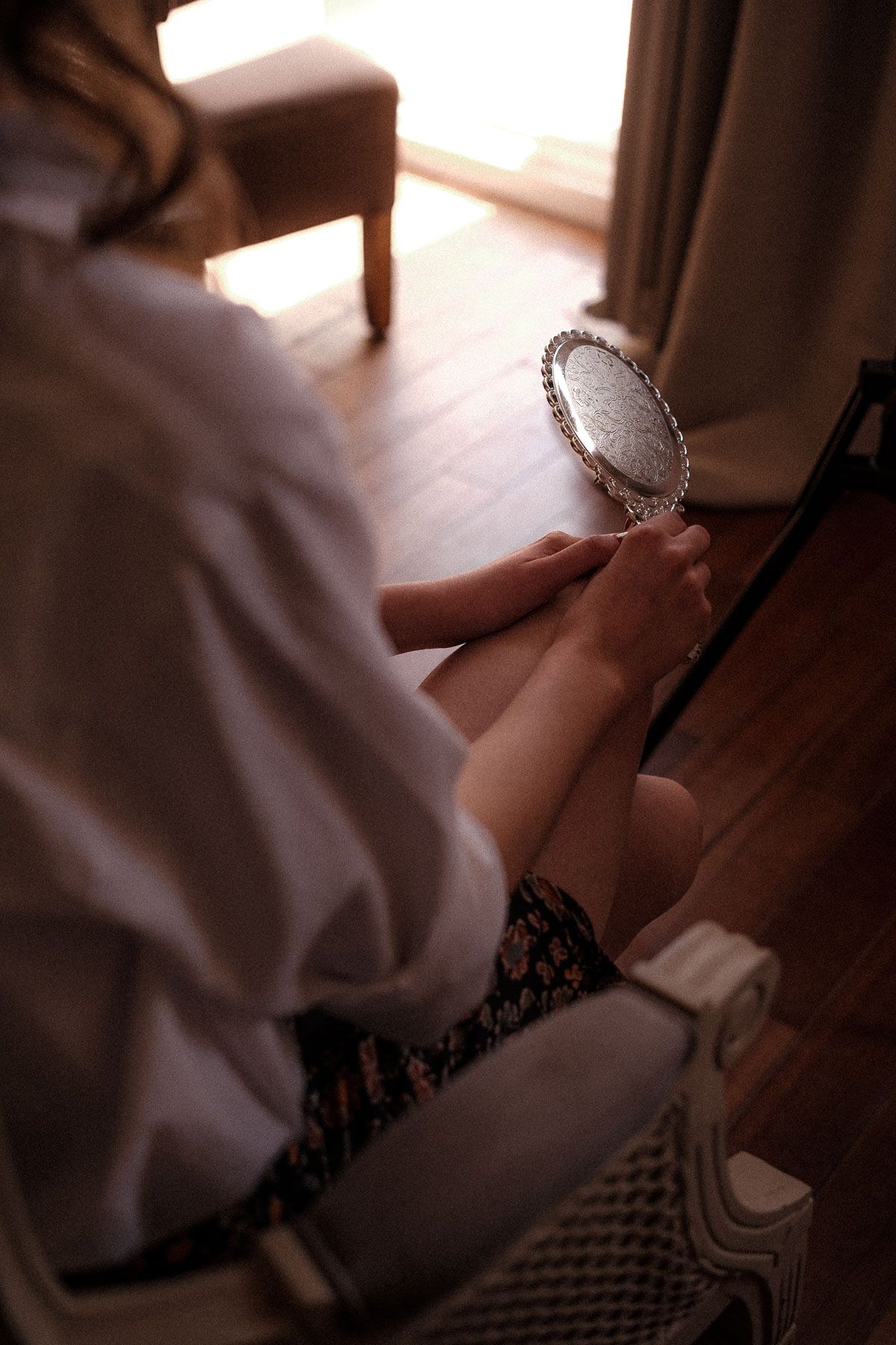 Close-up view of hands holding a small silver locket or pendant in warm lighting.