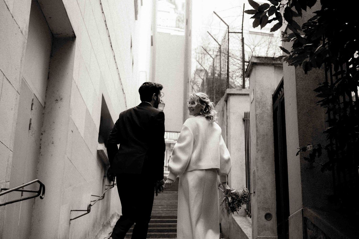 Black and white photo series showing couples walking up a staircase and through doorways in an architectural setting.