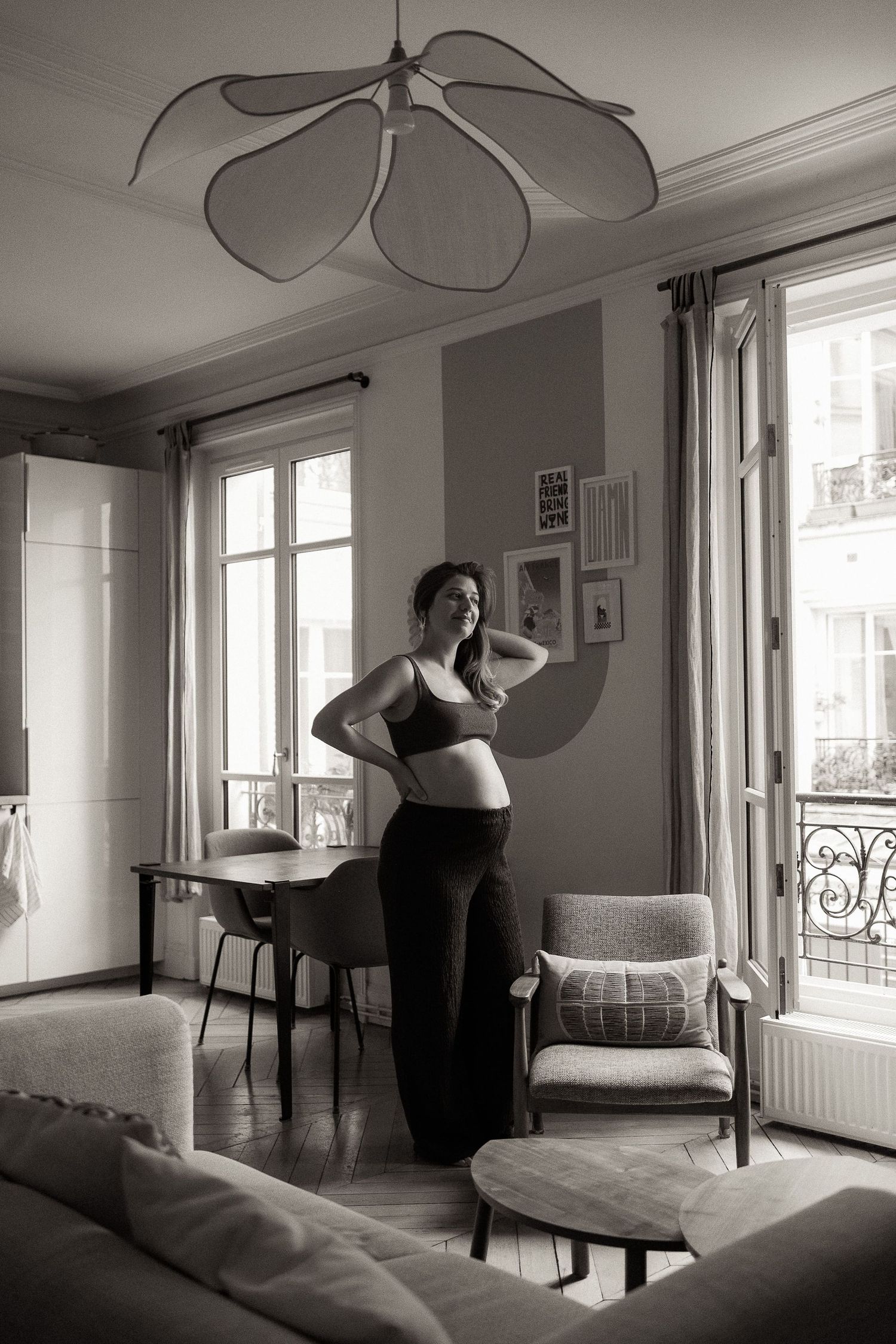 A series of black and white photos showing a figure dancing in an elegant room with large windows and minimalist decor.