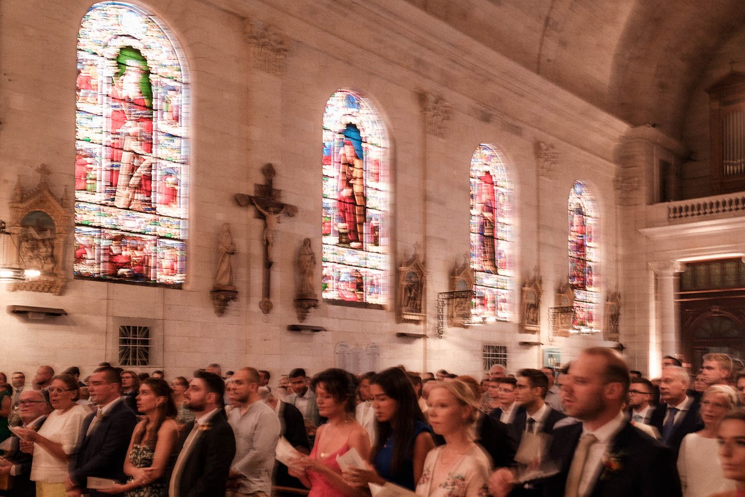 People gathered inside a historic church with stained glass windows during a religious service or ceremony.