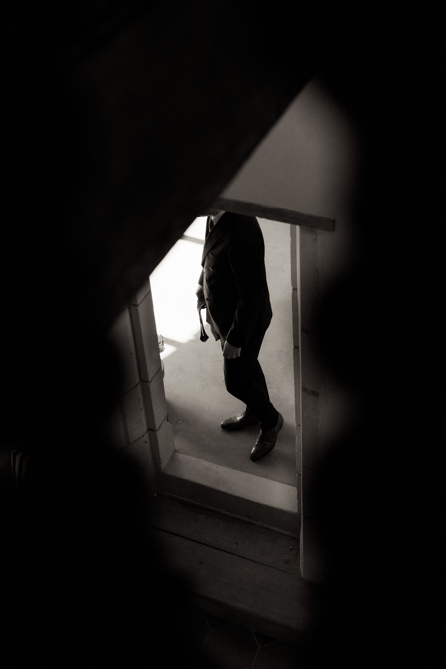 A series of dark silhouettes seen through a window frame create an eerie noir atmosphere in black and white.