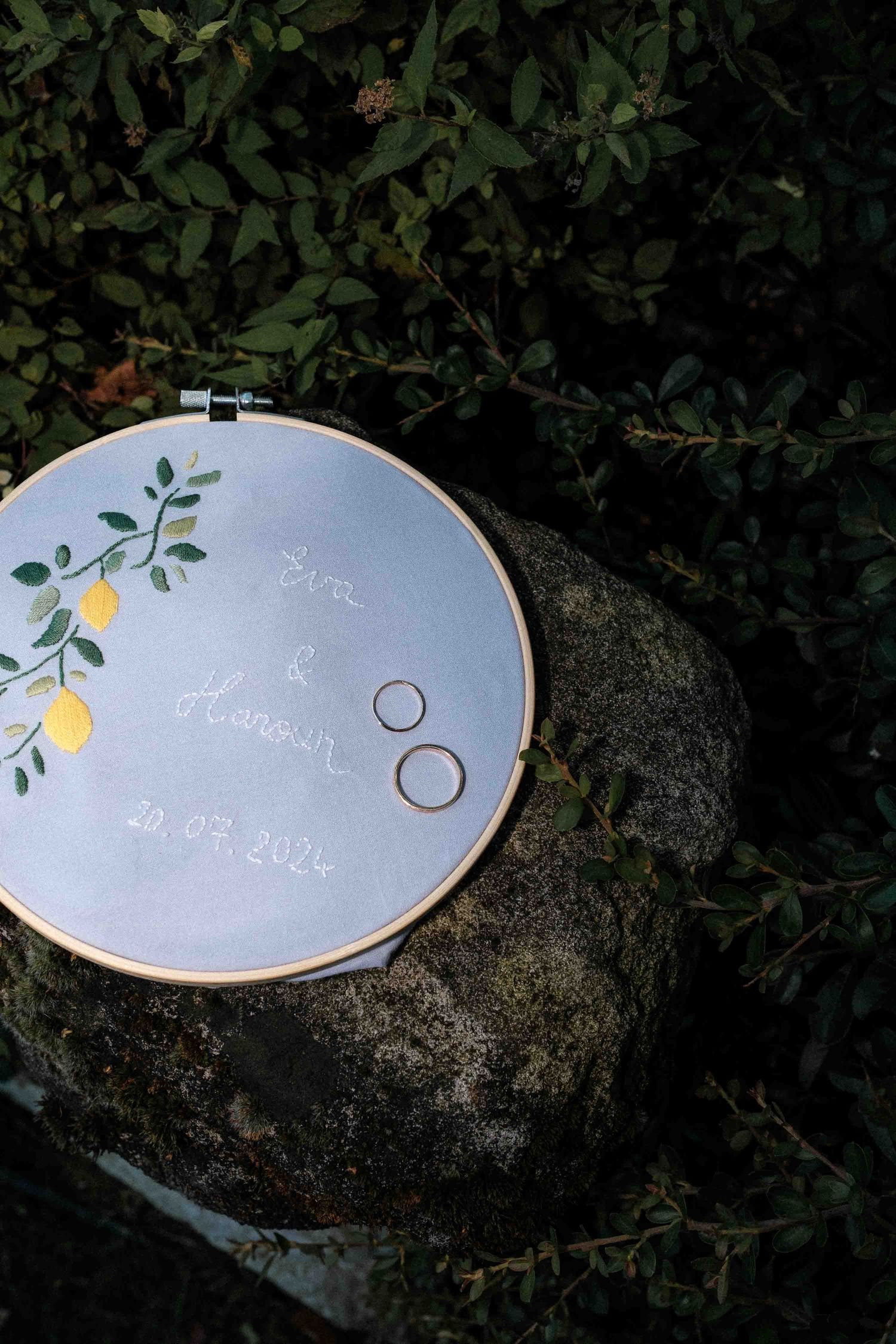 A light blue ceramic ring dish with delicate painted lemon and leaf designs displayed on a stone surface.