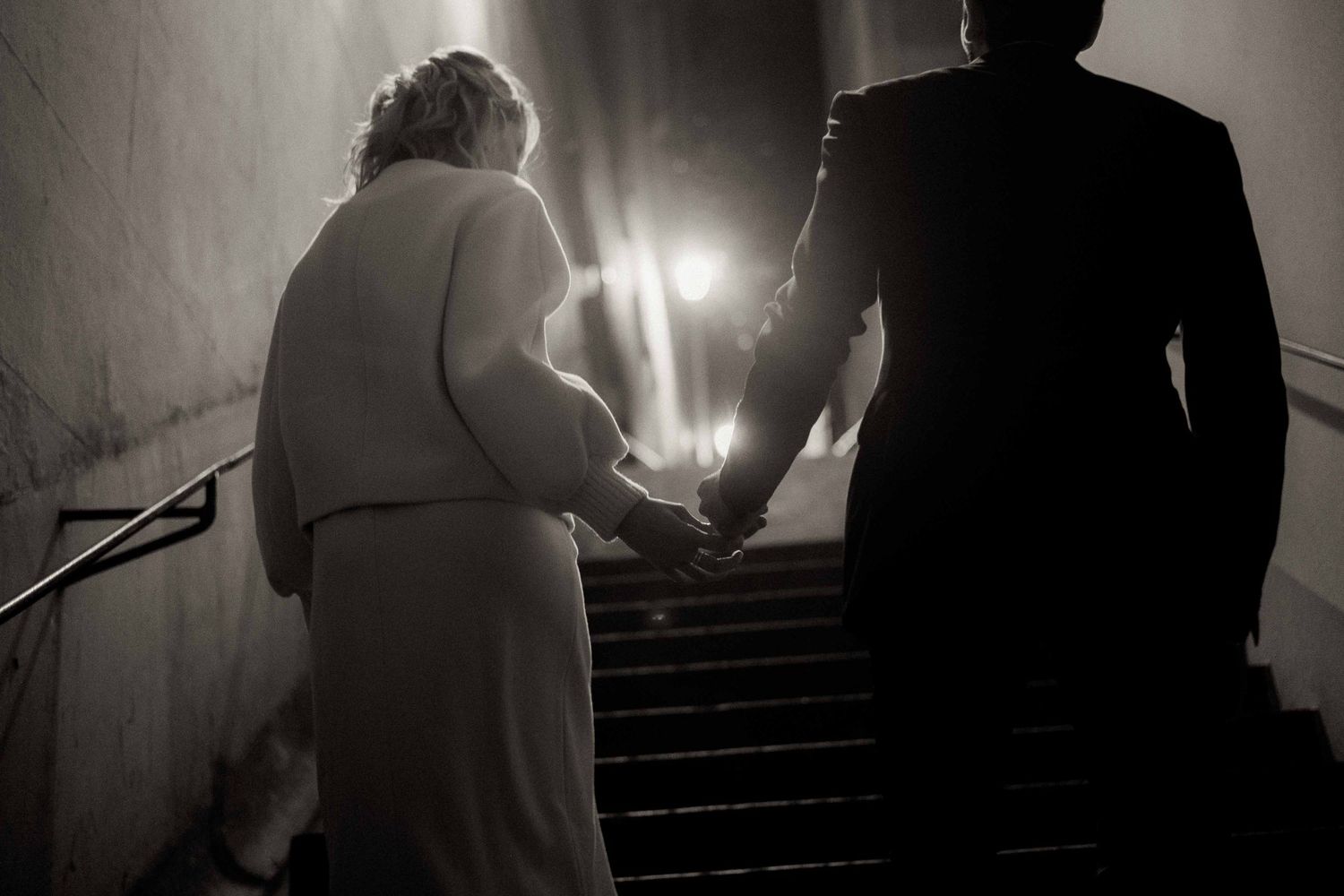 A dramatic black and white photo sequence shows silhouettes of figures ascending a dimly lit staircase.