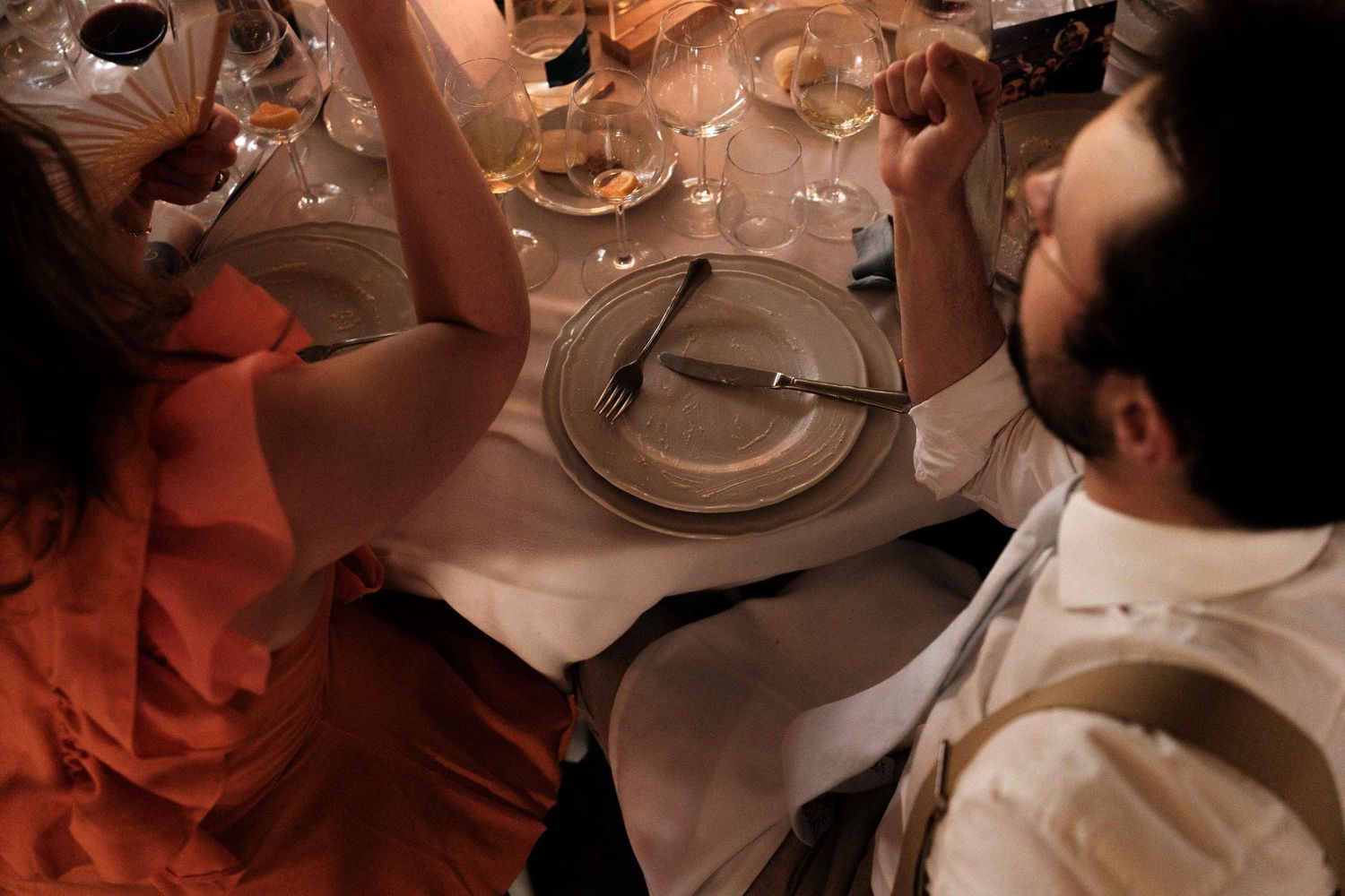 Diners seated at a restaurant table with wine glasses and plates during a fine dining experience.