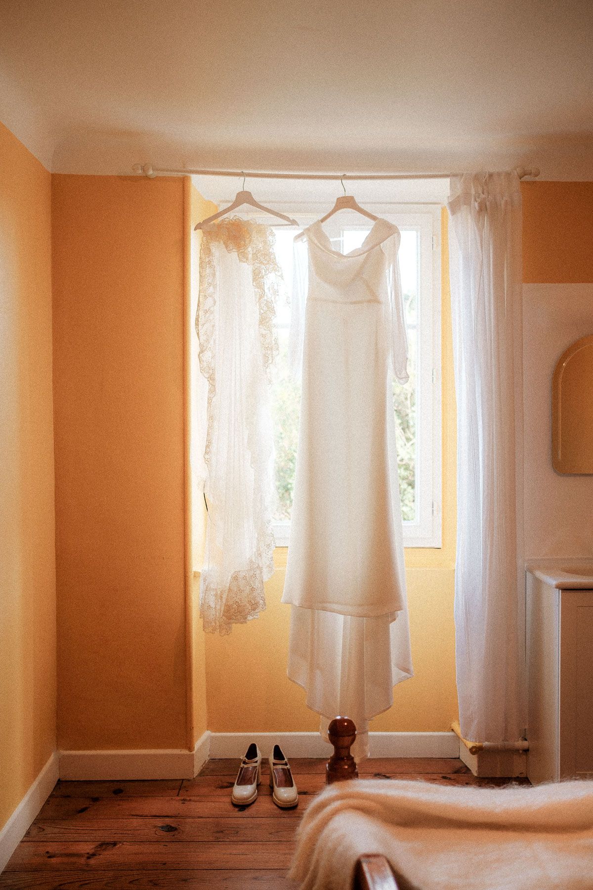 Sunlit interior room with white lace curtains and peach-colored walls creating a warm, inviting atmosphere.