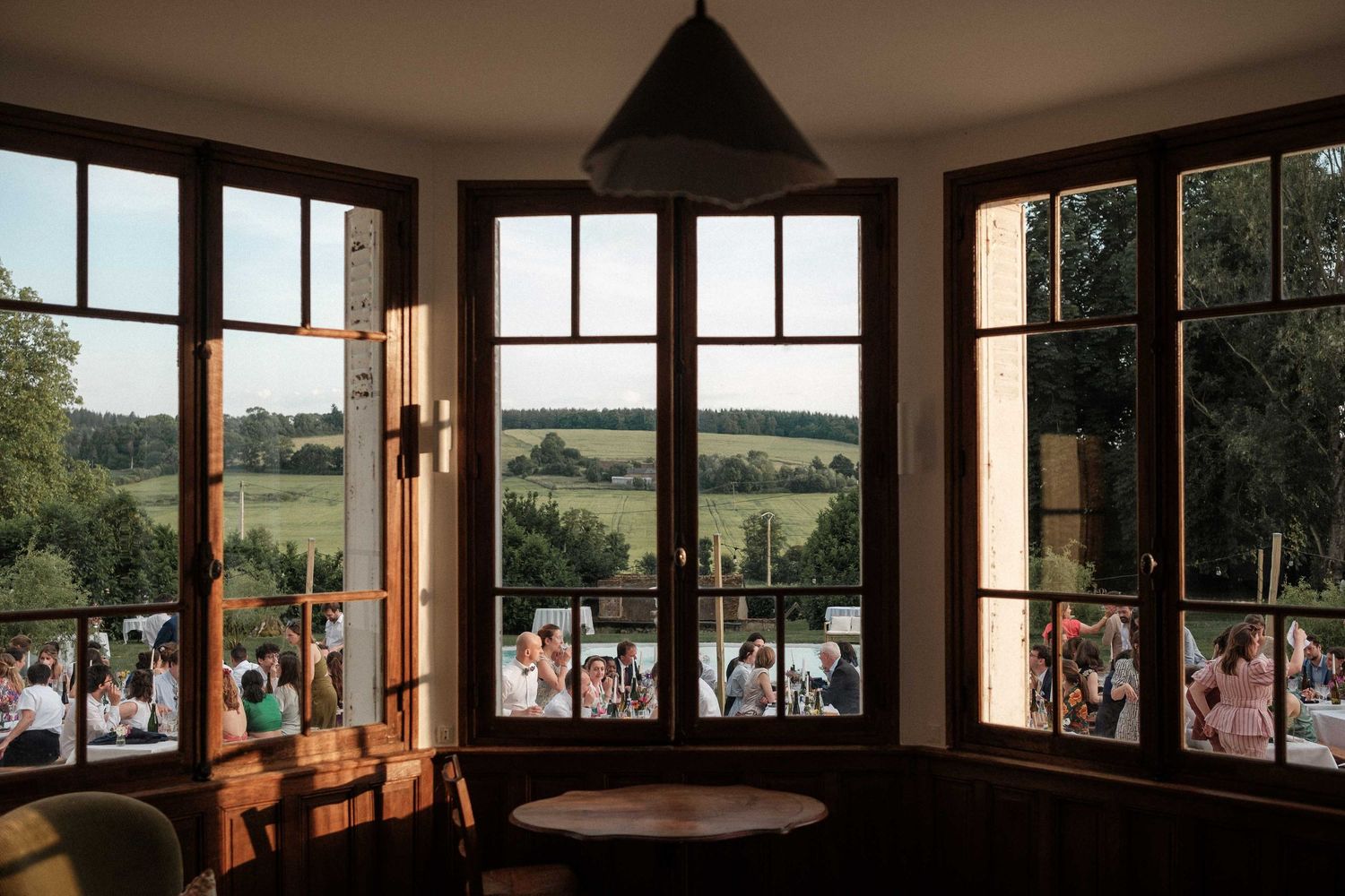 A panoramic view through multiple windows showing rolling green countryside and trees on a sunny day.