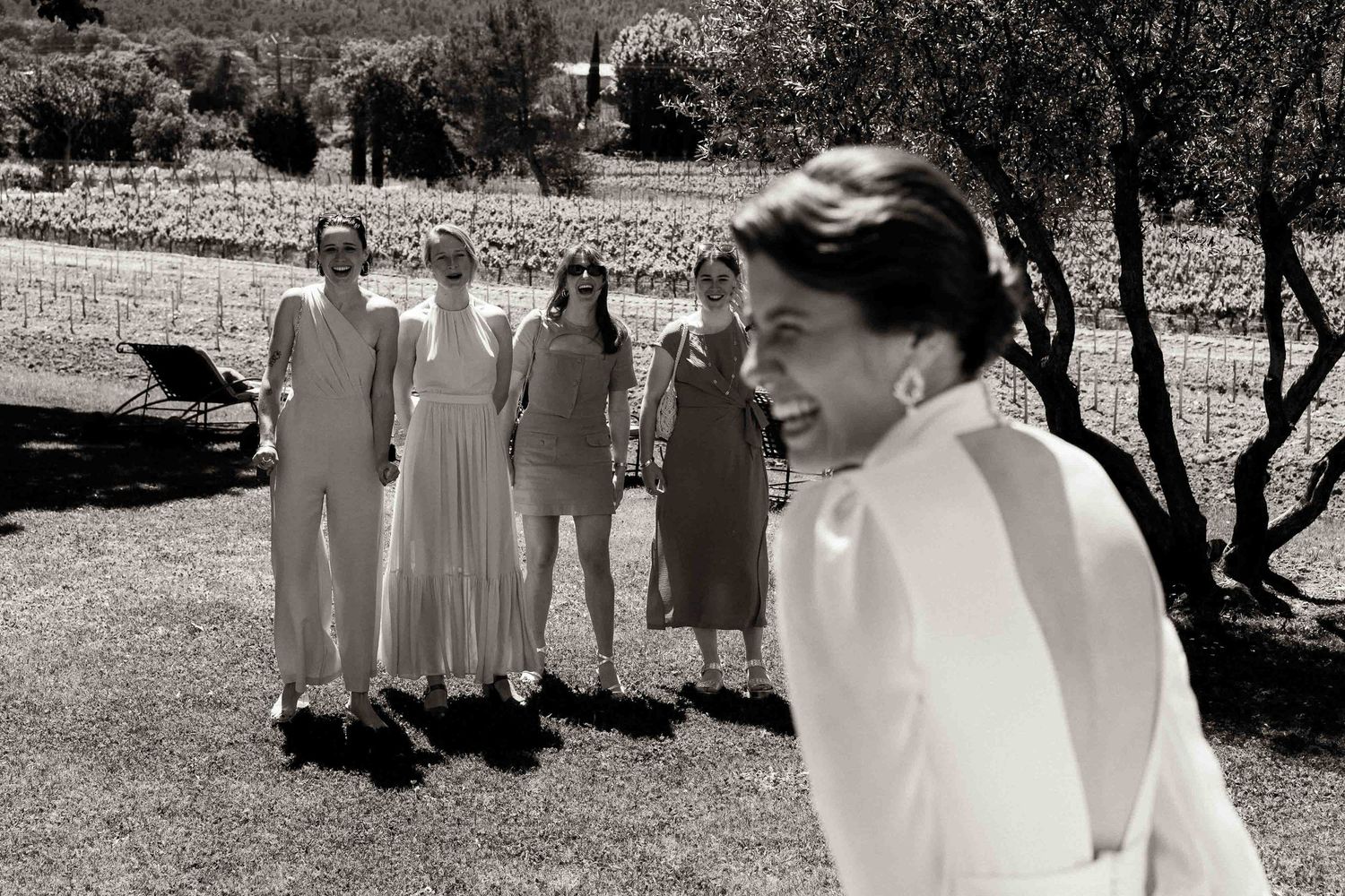 A group in white dresses walks together outdoors in a candid black and white photograph.