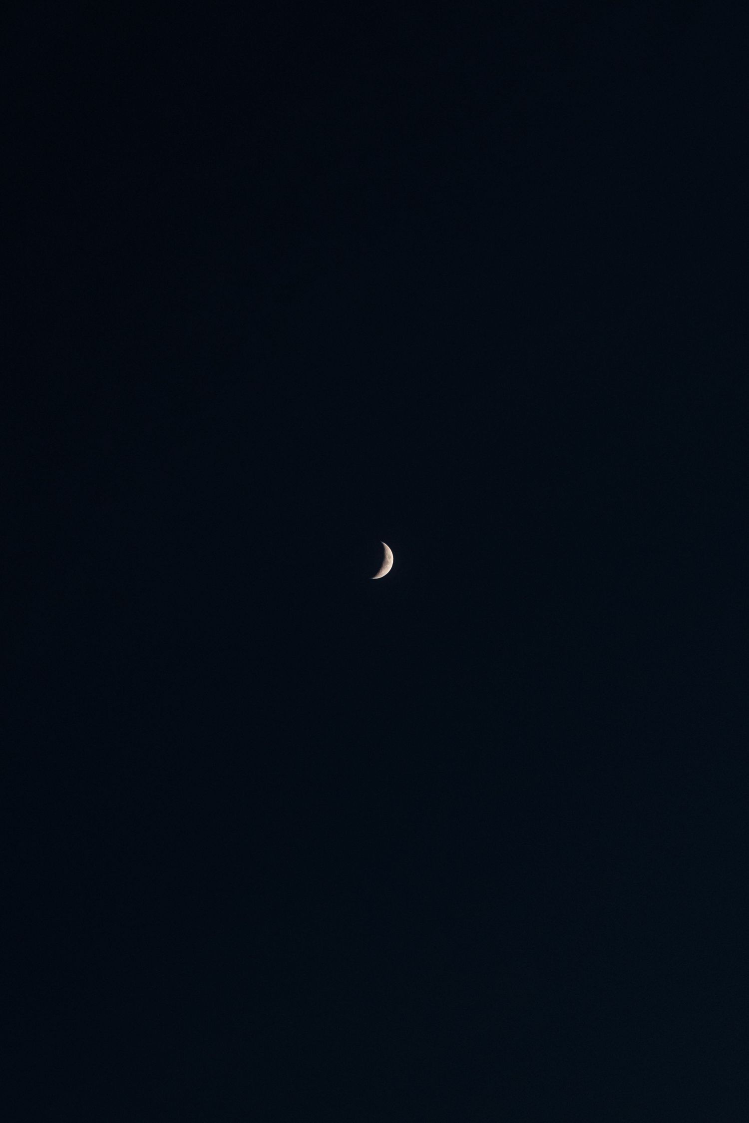 A crescent moon glows against a dark night sky in a minimalist celestial composition.