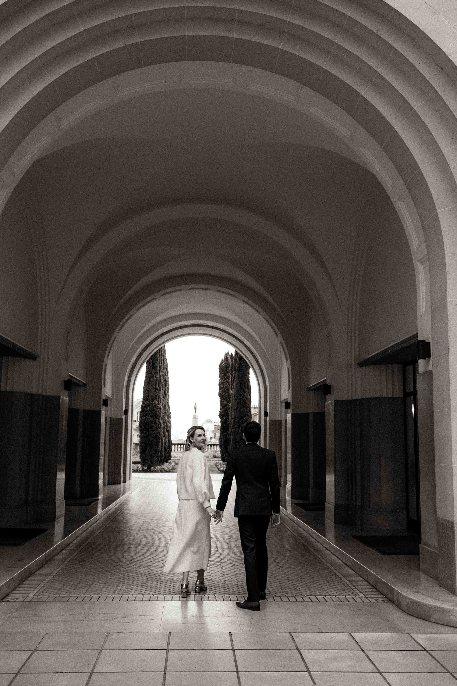 A series of five black and white photographs showing silhouettes of people walking through an arched hallway corridor.