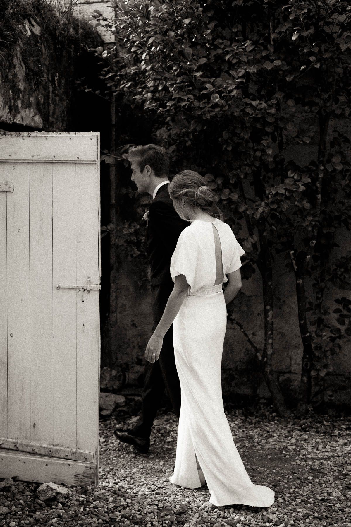 A sequence of black and white photos shows a person in a white dress approaching and disappearing behind a garden gate.