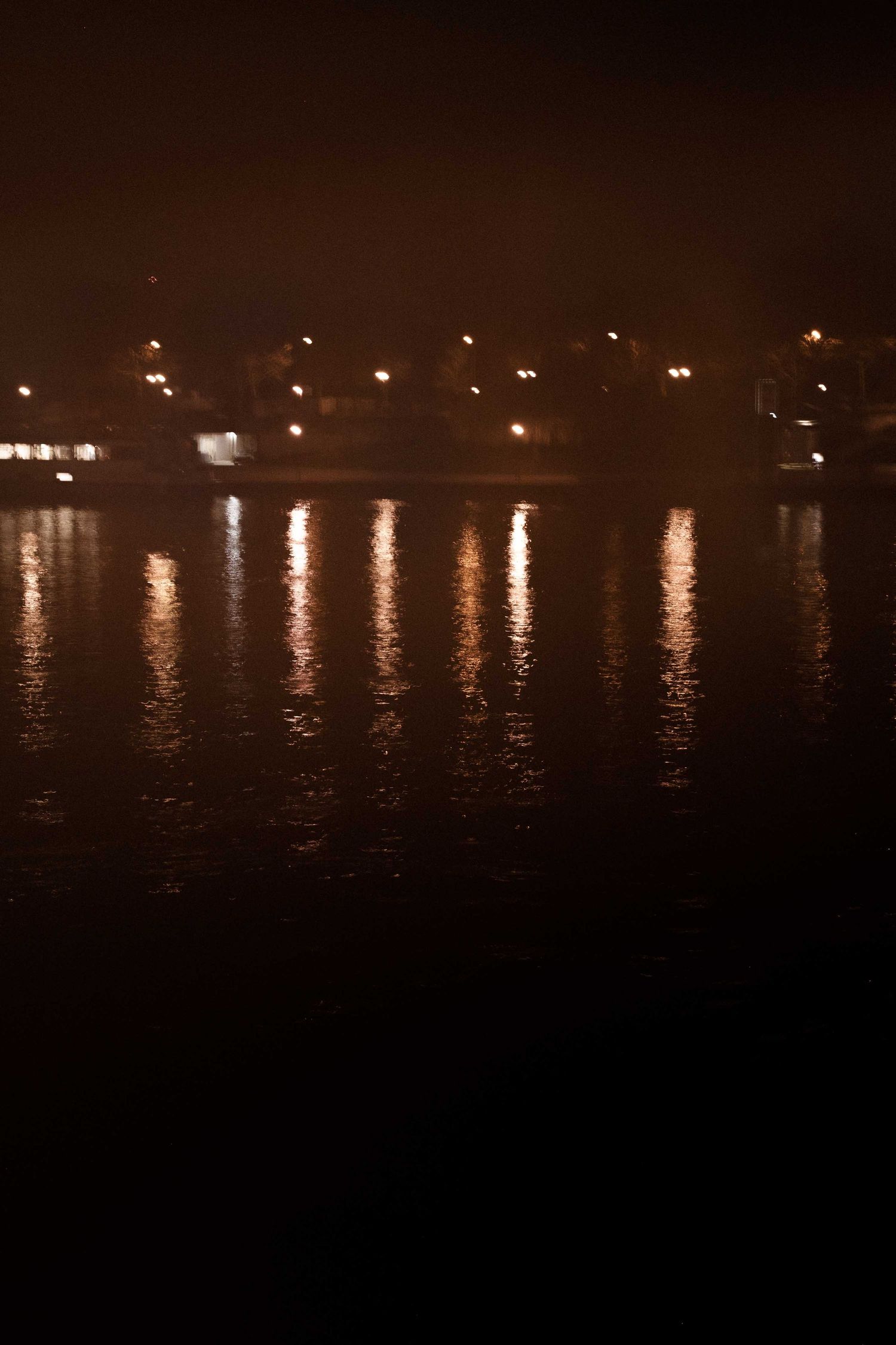 Nighttime waterfront scene with lights reflecting off calm water creating a serene ambiance.