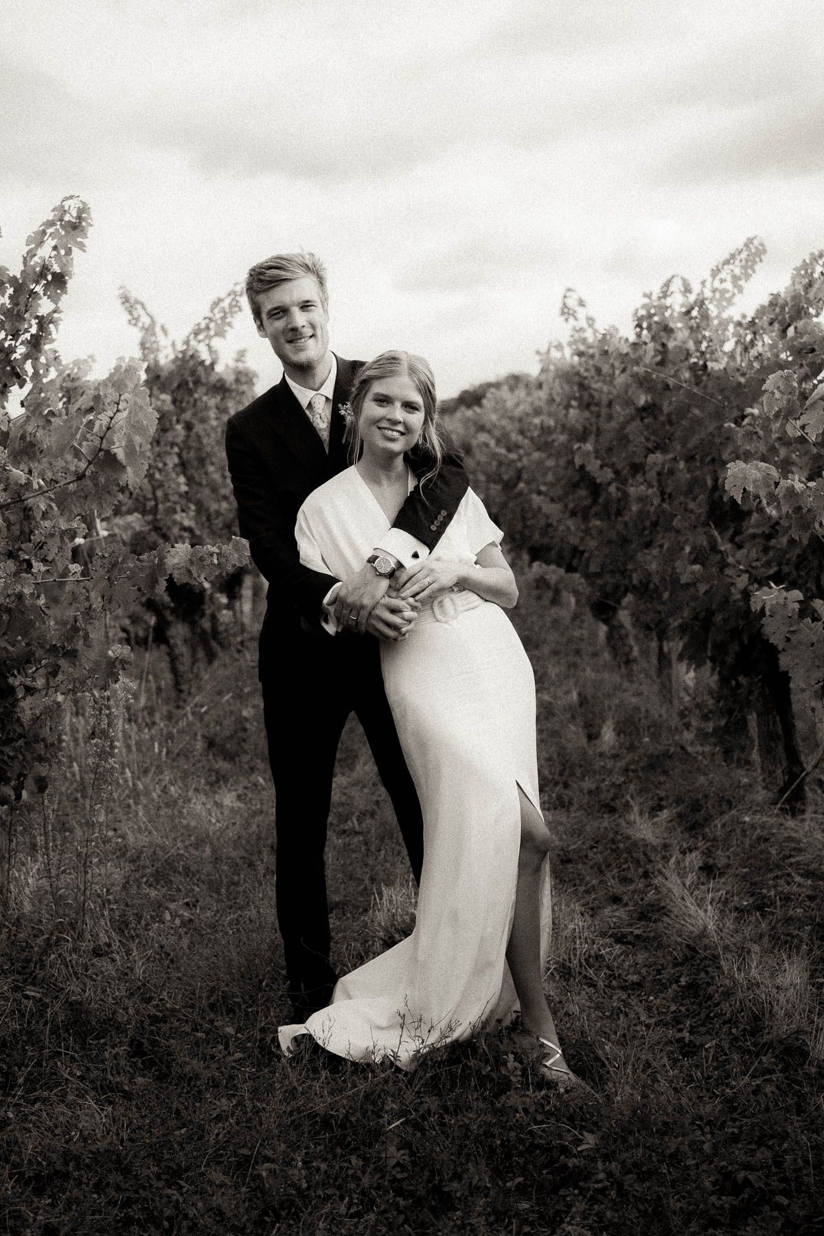A romantic black and white wedding photo series showing a couple embracing in a natural outdoor setting.