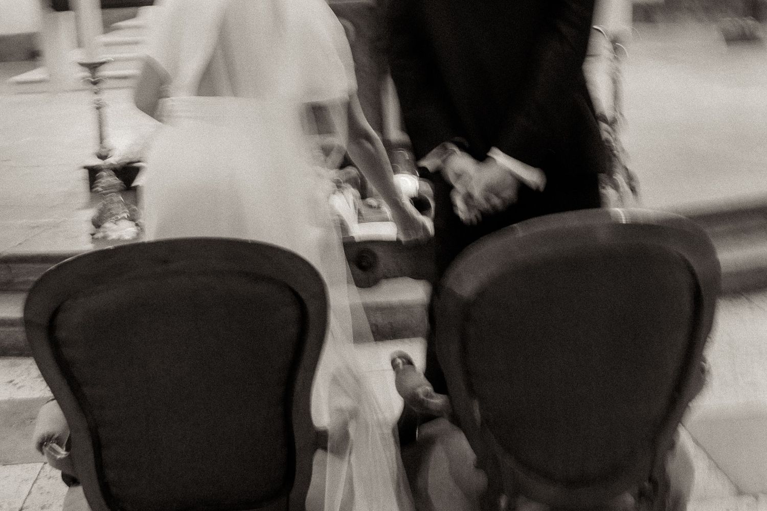 A blurred black and white photo shows two office chairs at a desk in a busy indoor setting.