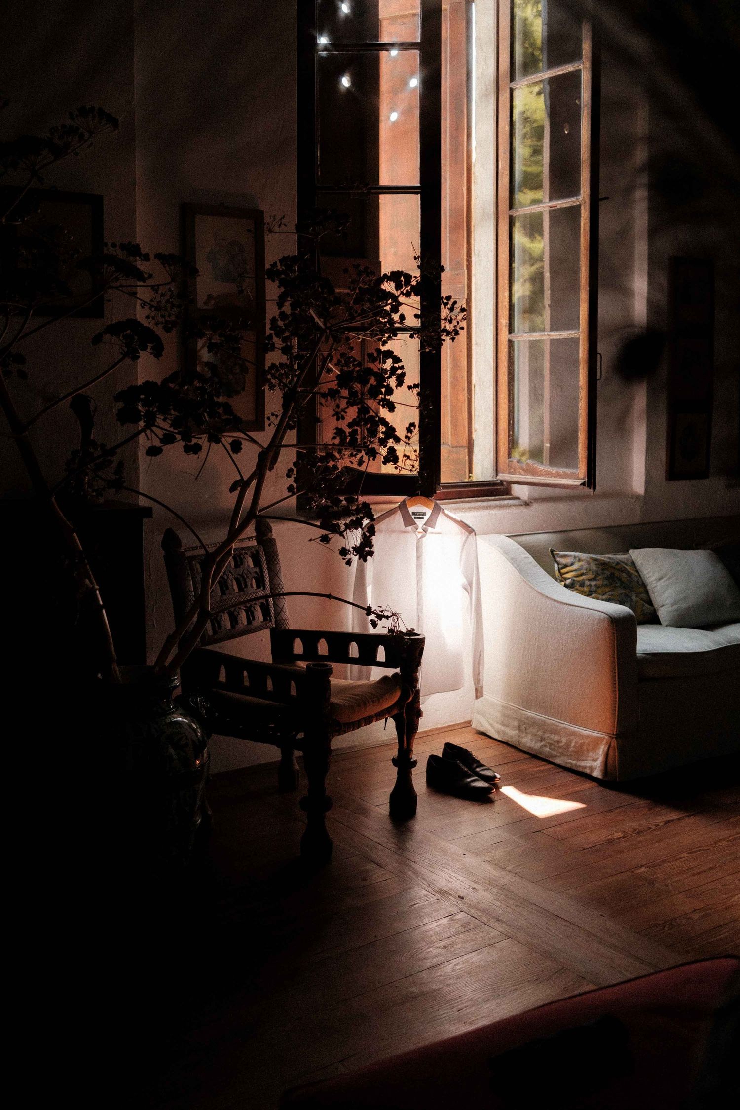 Sunlight streams through a window into a dark room, casting dramatic shadows on wooden floors and furniture.