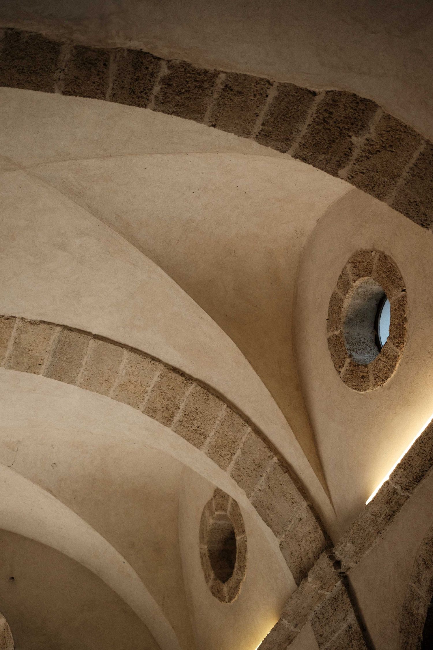 Stone vaulted ceiling with arches and circular windows in a historic church interior.