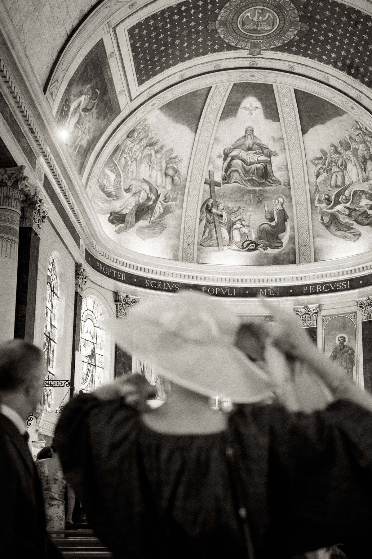 Black and white panoramic sequence showing silhouettes of figures viewing ornate church ceiling murals and architecture.