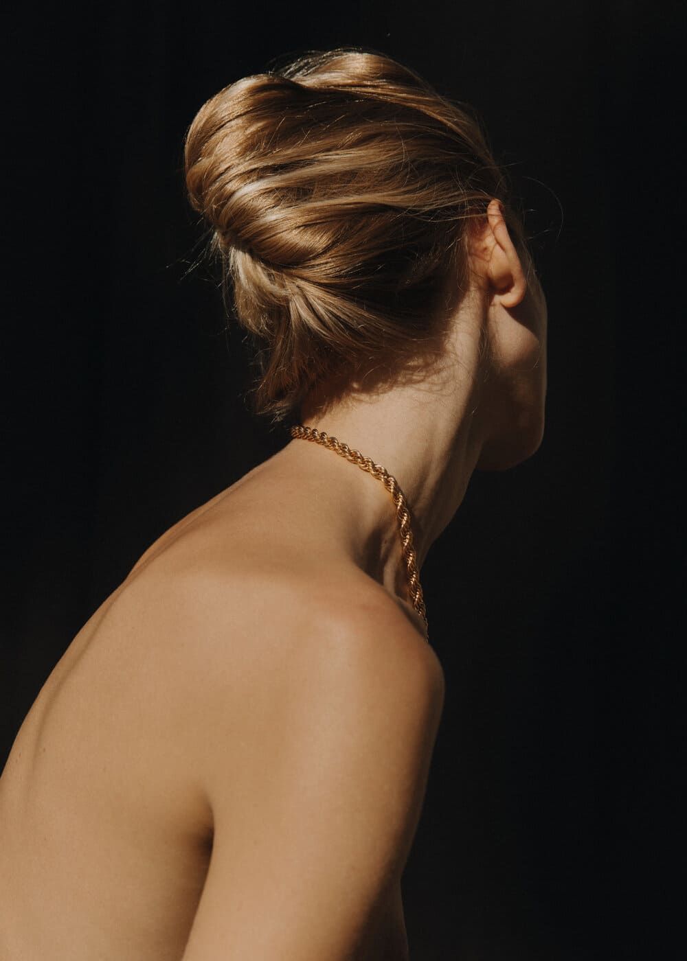 A series of profile portraits showing a gold chain necklace against bare shoulders on a dark background.