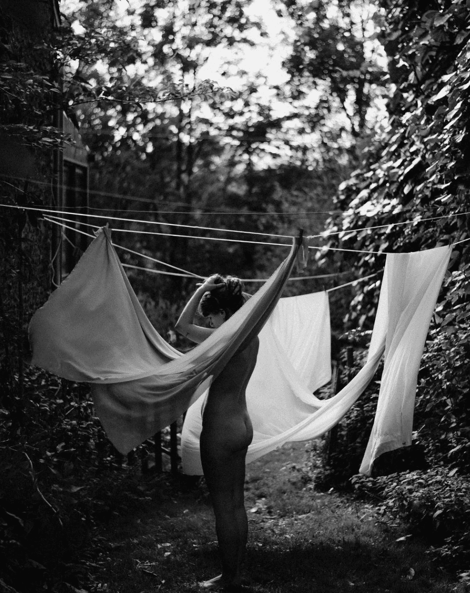 Black and white photographs show white laundry hanging on clotheslines between trees in a garden setting.