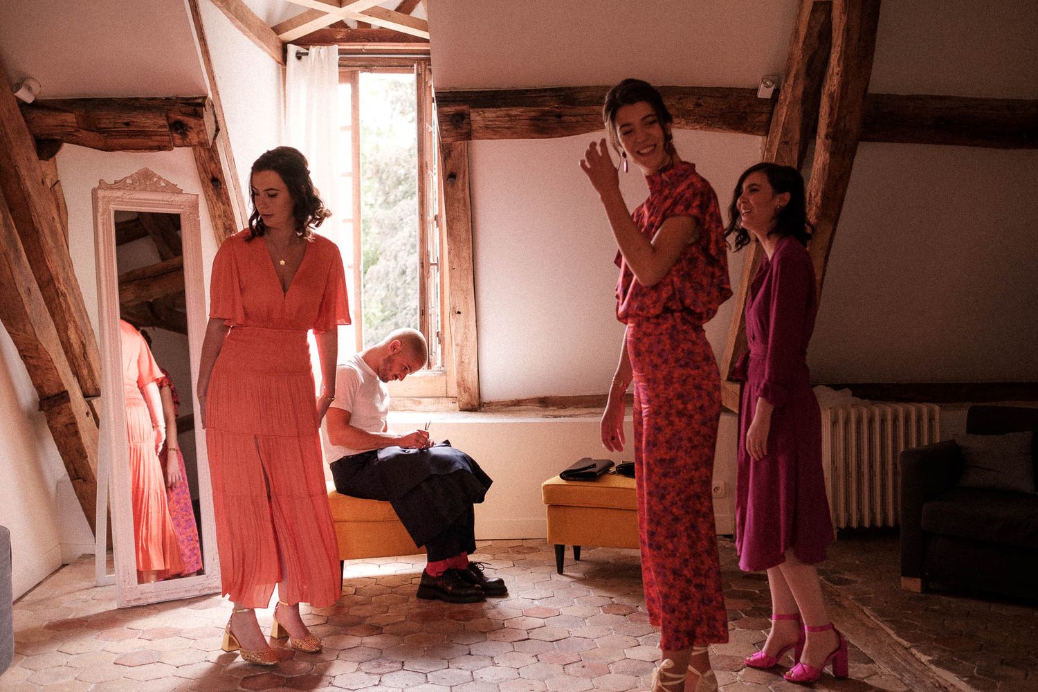 A series of connected photos showing people in pink and coral dresses walking through a light-filled hallway.