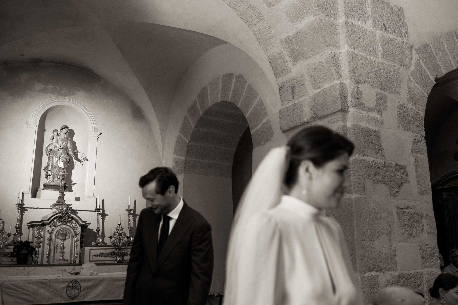 A series of black and white wedding photographs showing couples in a stone church with arched architecture and dramatic lighting.