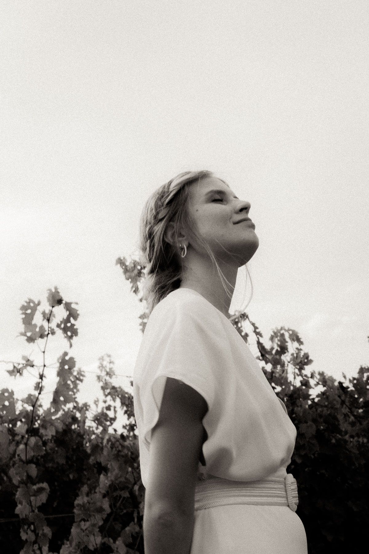 A series of artistic black and white portraits taken in a vineyard with trees in the background.