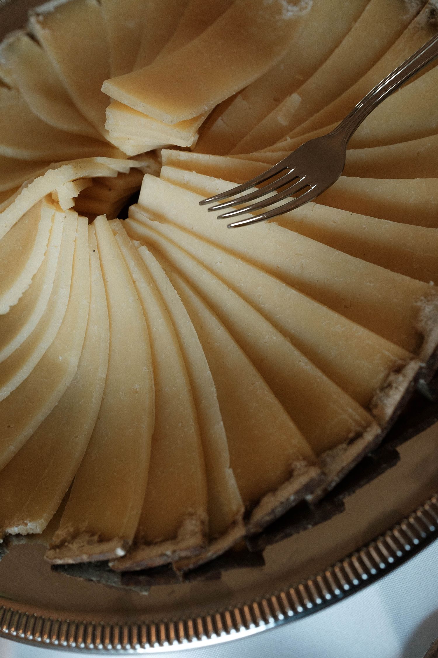 Close-up view of a creamy pie with perfectly pleated edges and smooth texture on a silver serving plate.
