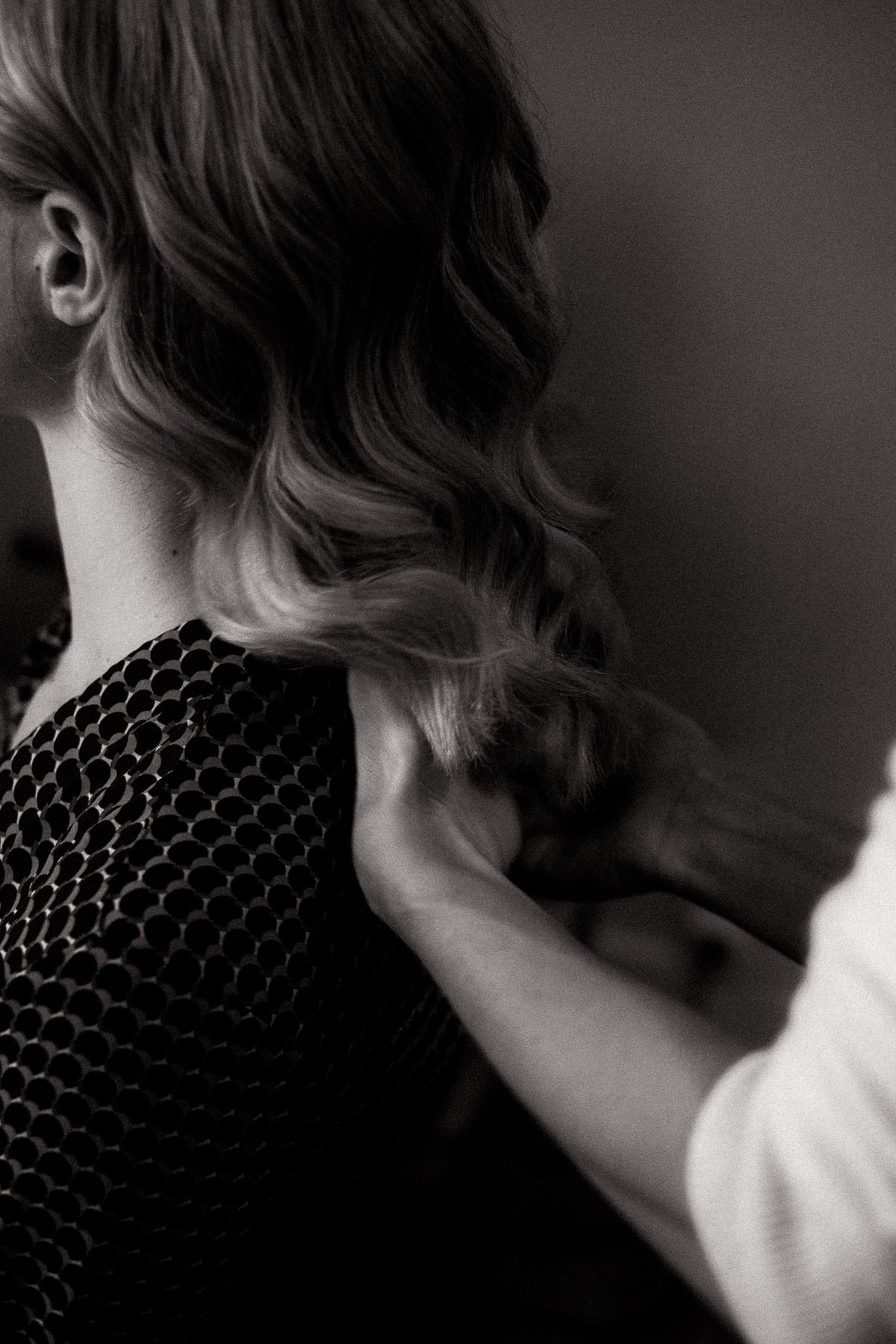 Black and white close-up of wavy hair and textured knit sweater showing elegant styling details.