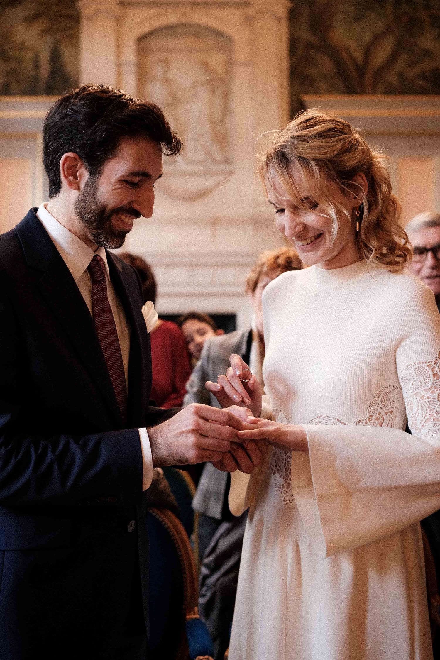 A couple exchanges rings during an intimate wedding ceremony in an elegant indoor venue.
