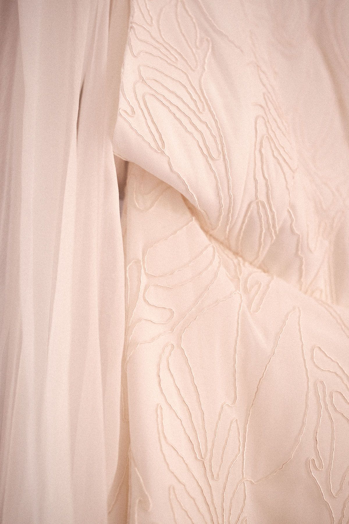Delicate white fabric with soft pleats and folds creates an ethereal textural pattern in natural light.