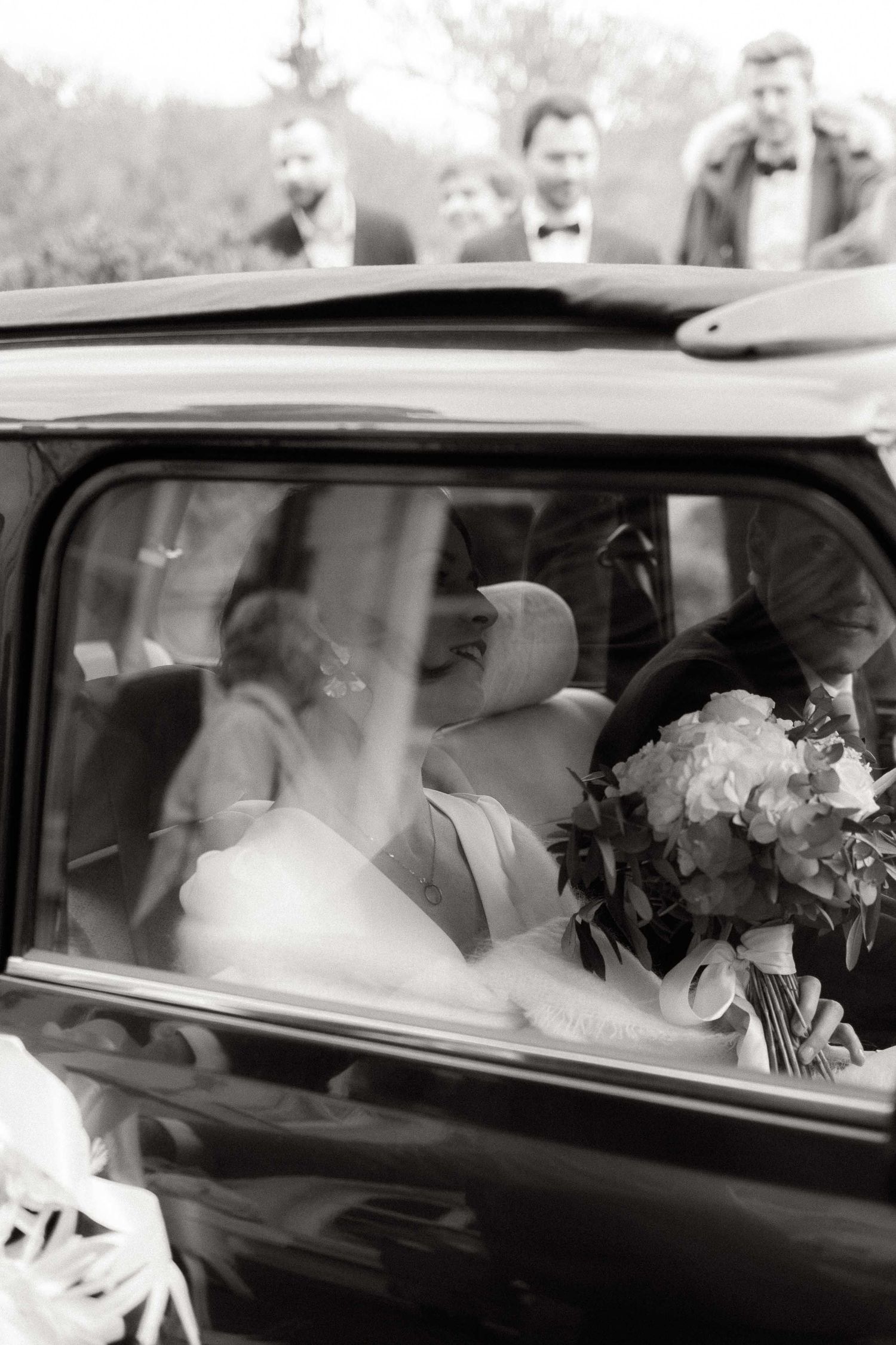 A black and white photo series showing a bride and groom in a classic car through multiple window frames.