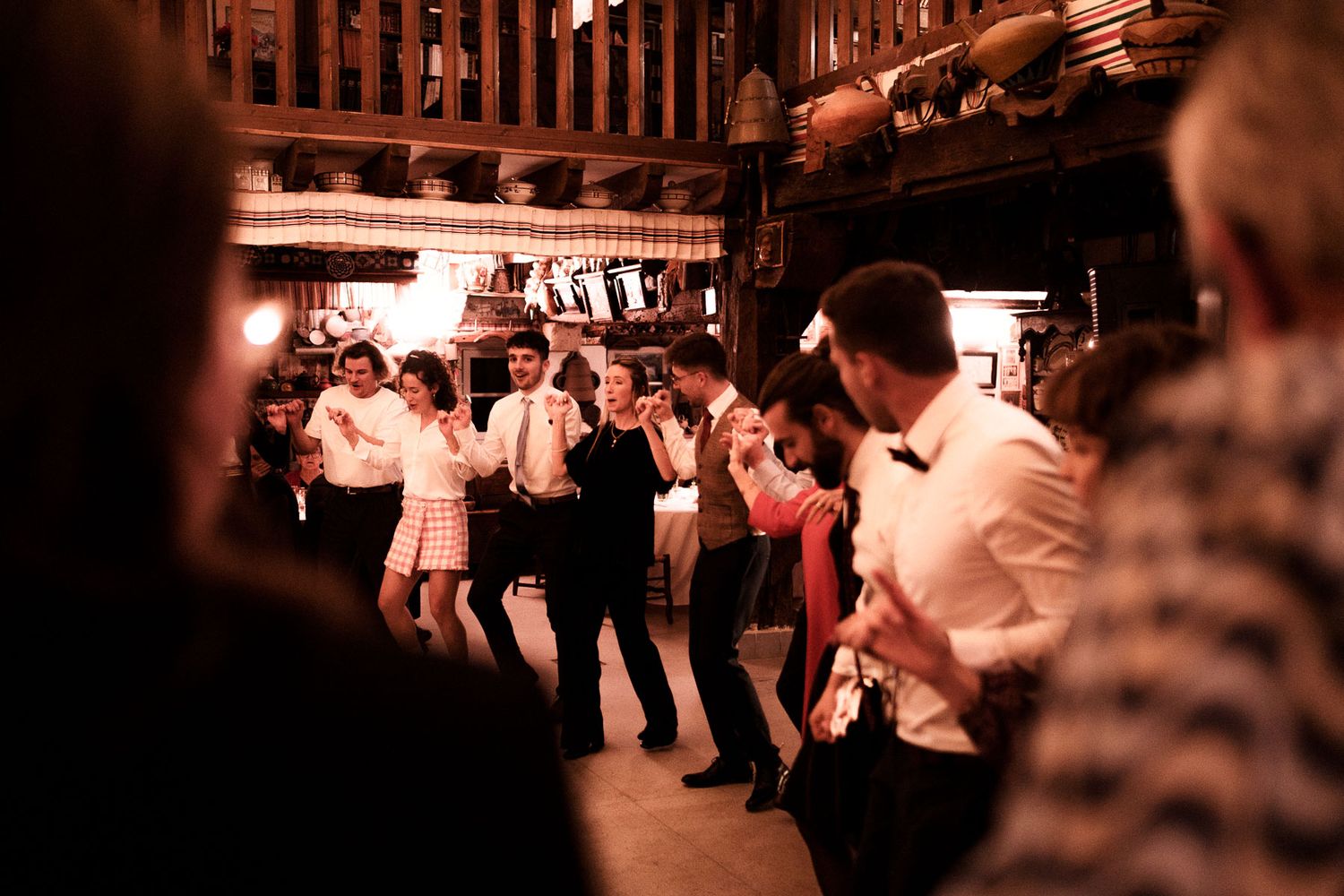 Couples dance together on a dimly lit dance floor at a social gathering with warm lighting and blurred motion.