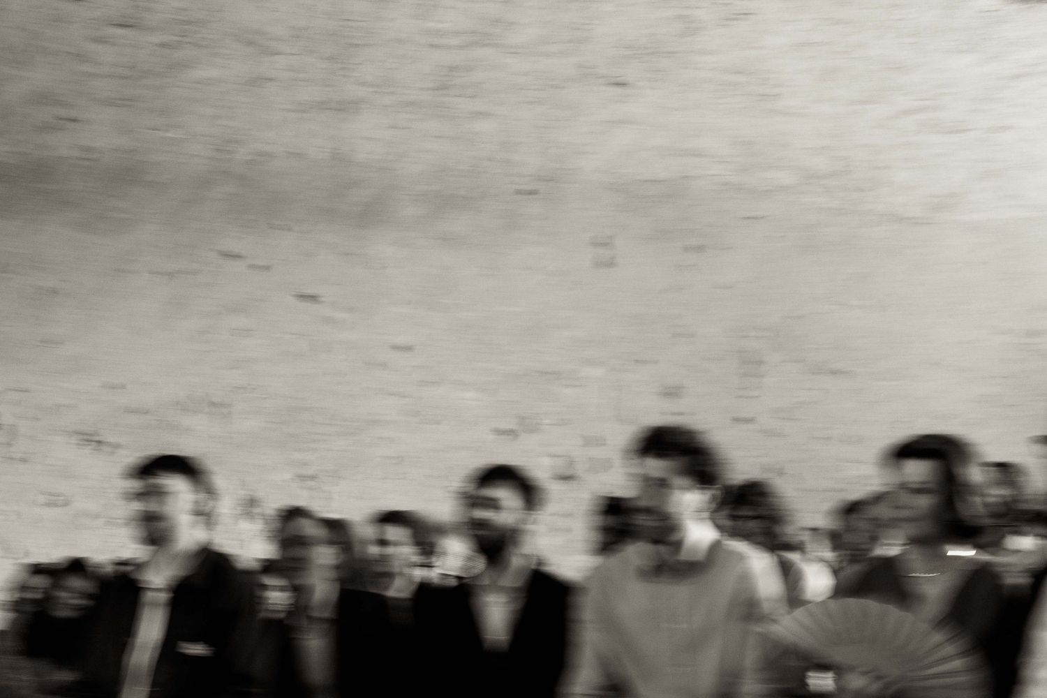 A blurred artistic black and white photograph showing a crowd of people standing together.