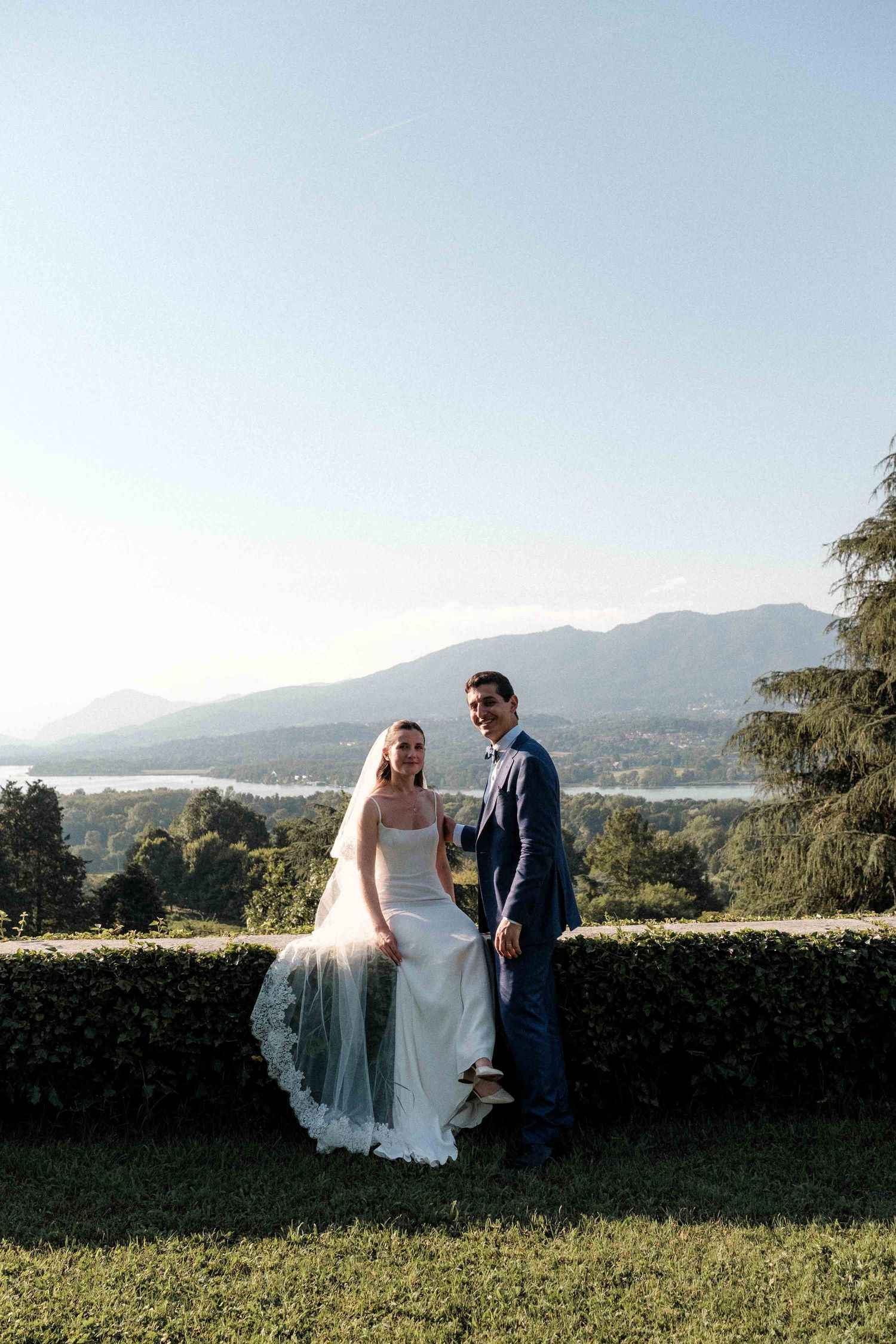 A wedding couple stands in a scenic mountain landscape during sunset while sharing intimate moments together.