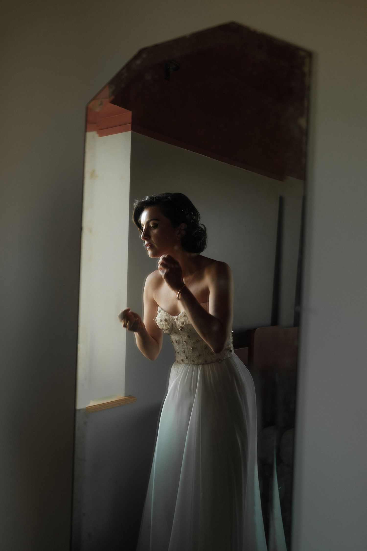 A series of moody photos showing someone in a flowing white dress standing by a window in dramatic lighting.