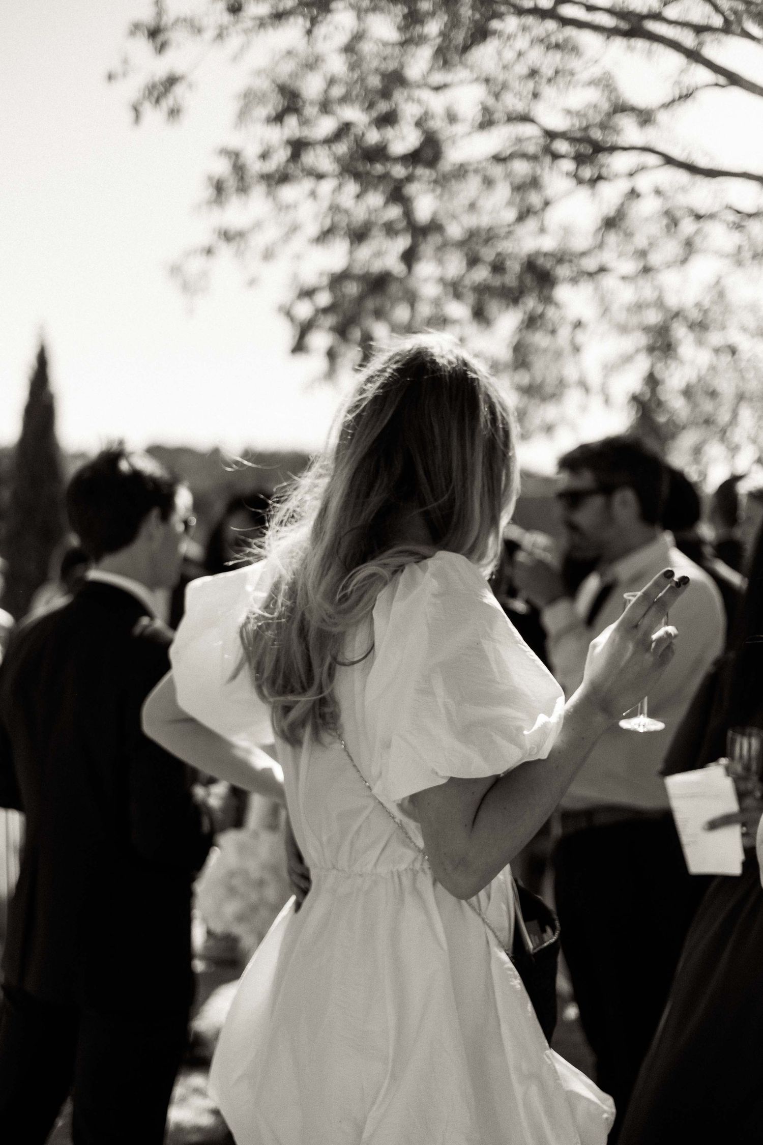 A couple shares a romantic dance at their wedding reception while guests look on in black and white.