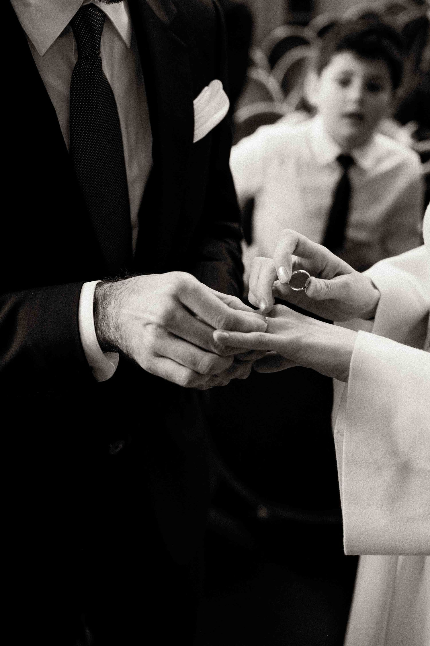 Black and white close-up photo of hands exchanging wedding rings during a ceremony.