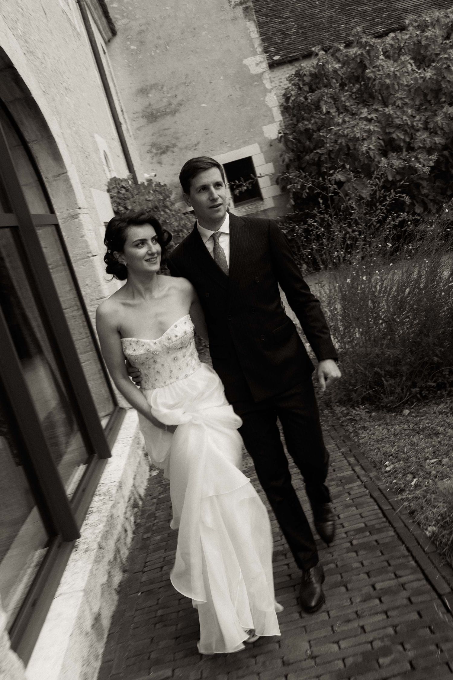 Vintage black and white wedding photo sequence showing couple walking and posing together on cobblestone path.