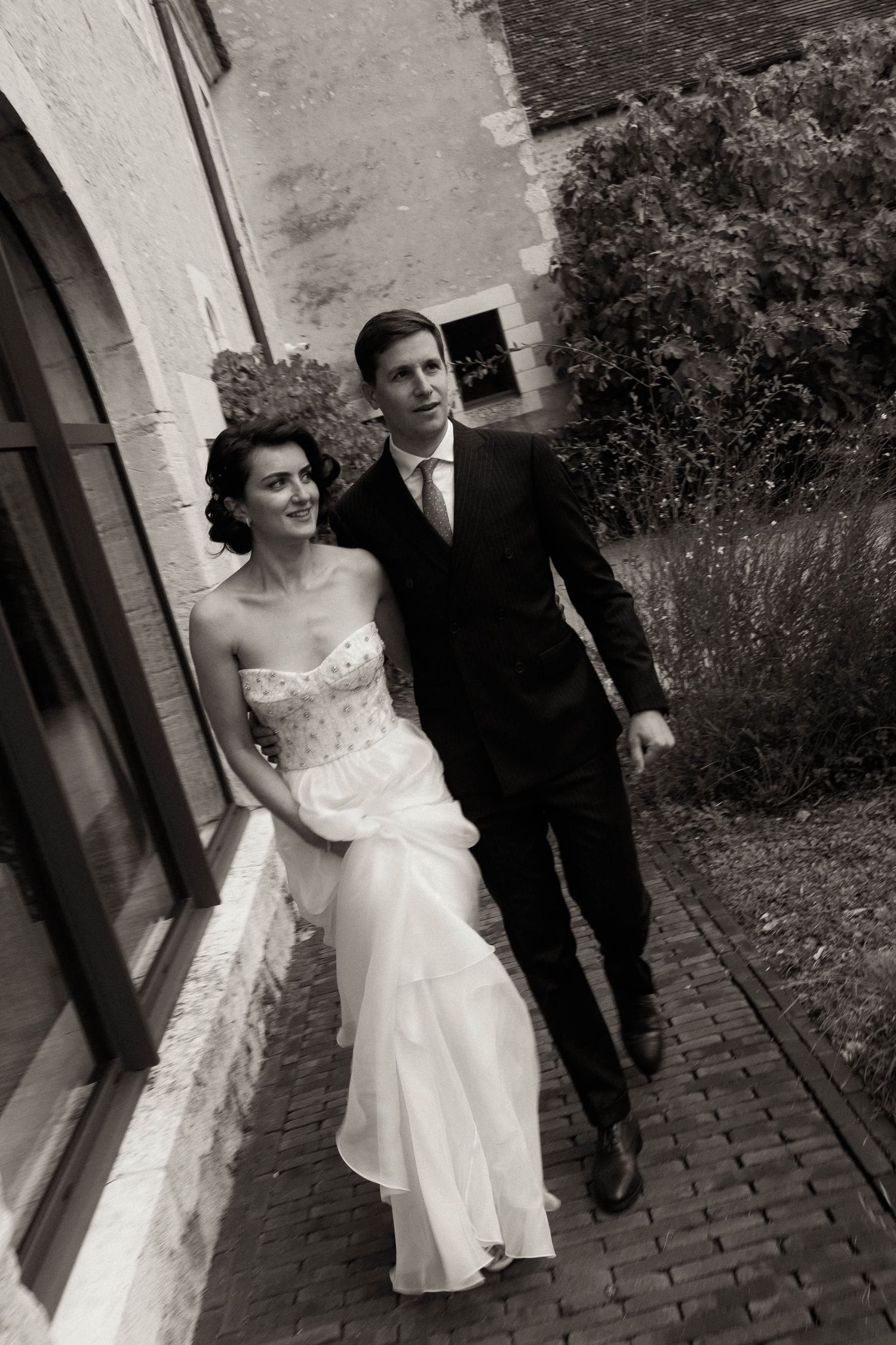 A vintage black and white wedding photo sequence showing a couple walking together on a cobblestone path.