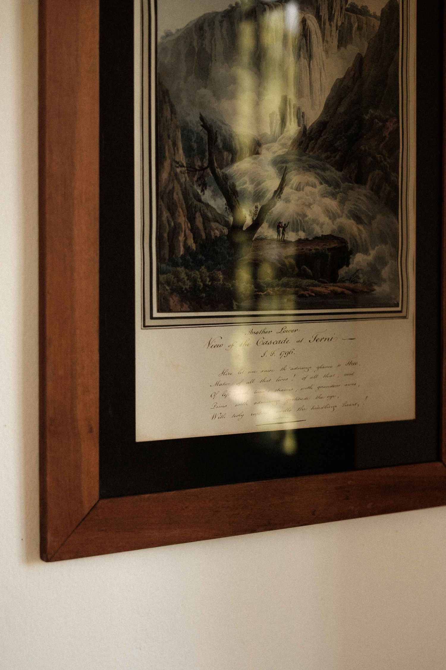 Three framed landscape artworks with mountain scenes hang on a white wall with wooden frames.