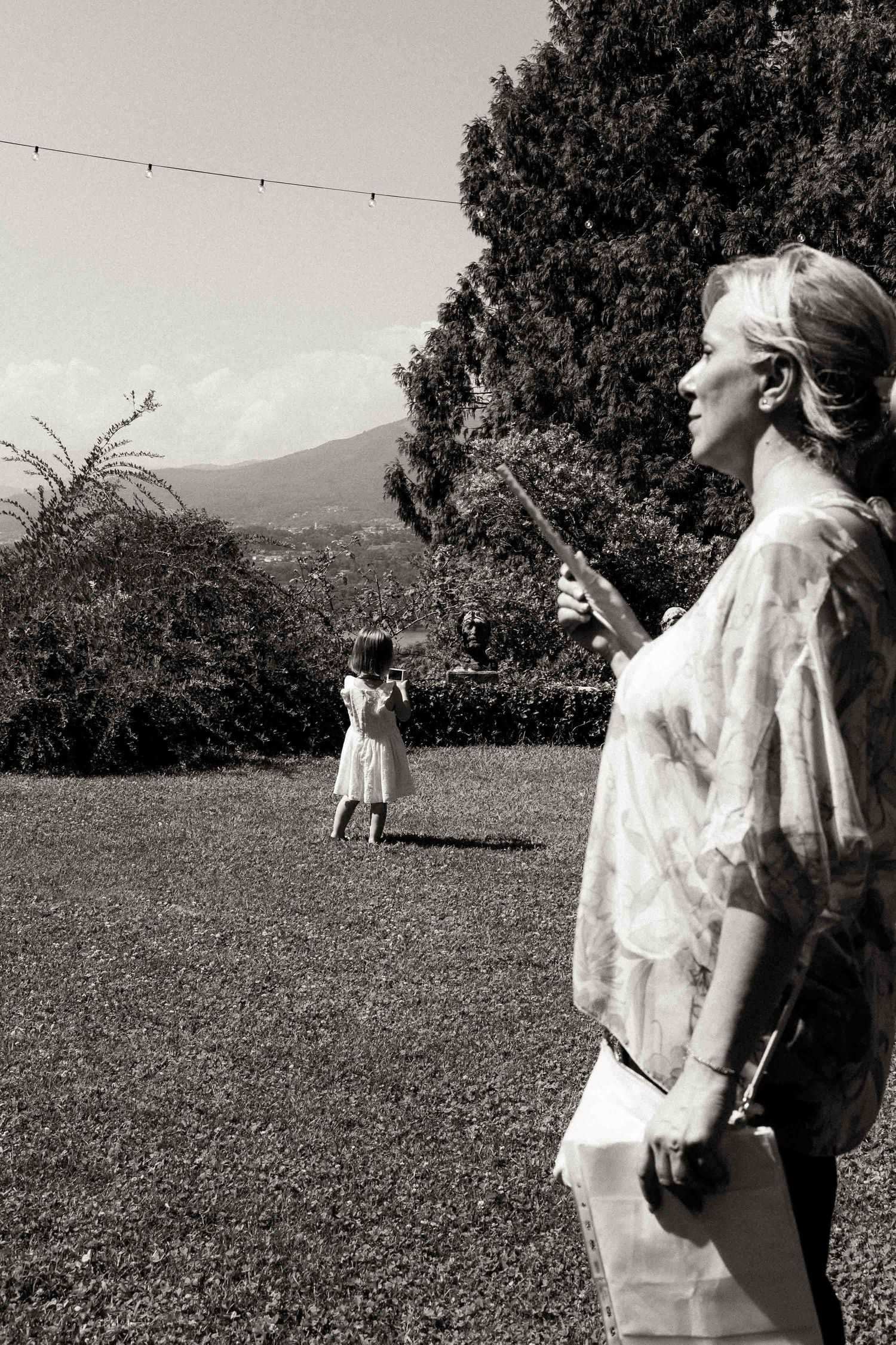 A series of black and white photos showing people in white clothing dancing and moving in an outdoor field with mountains.