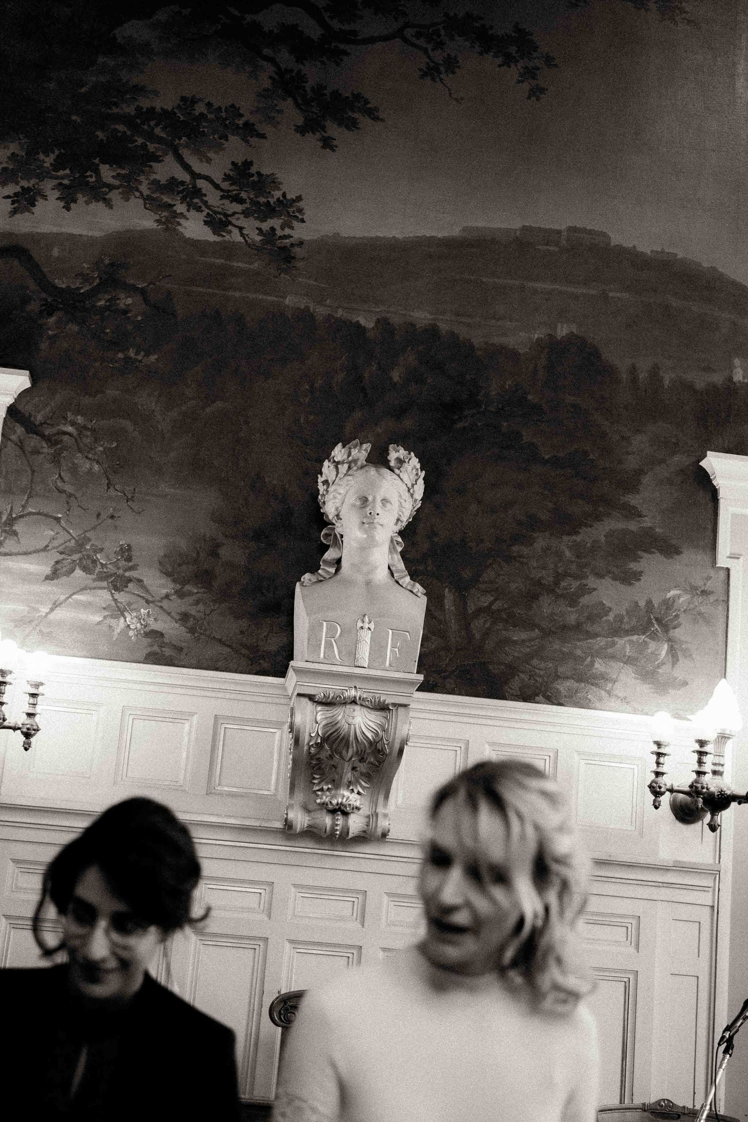 A series of blurry black and white photos showing silhouettes against a decorative wall with ornate paneling.
